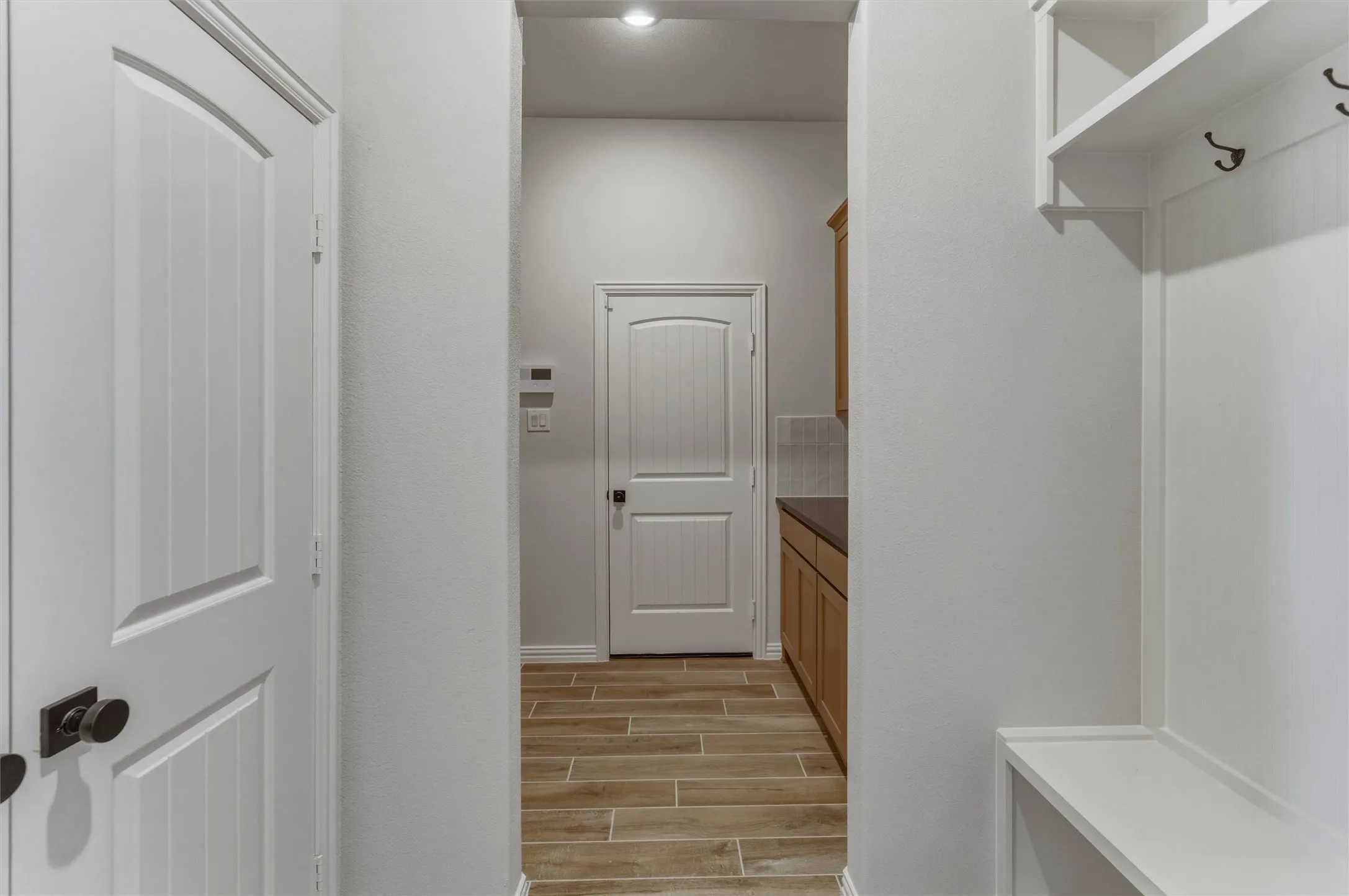 Hallway featuring wood-finish flooring and white interior doors with dark hardware