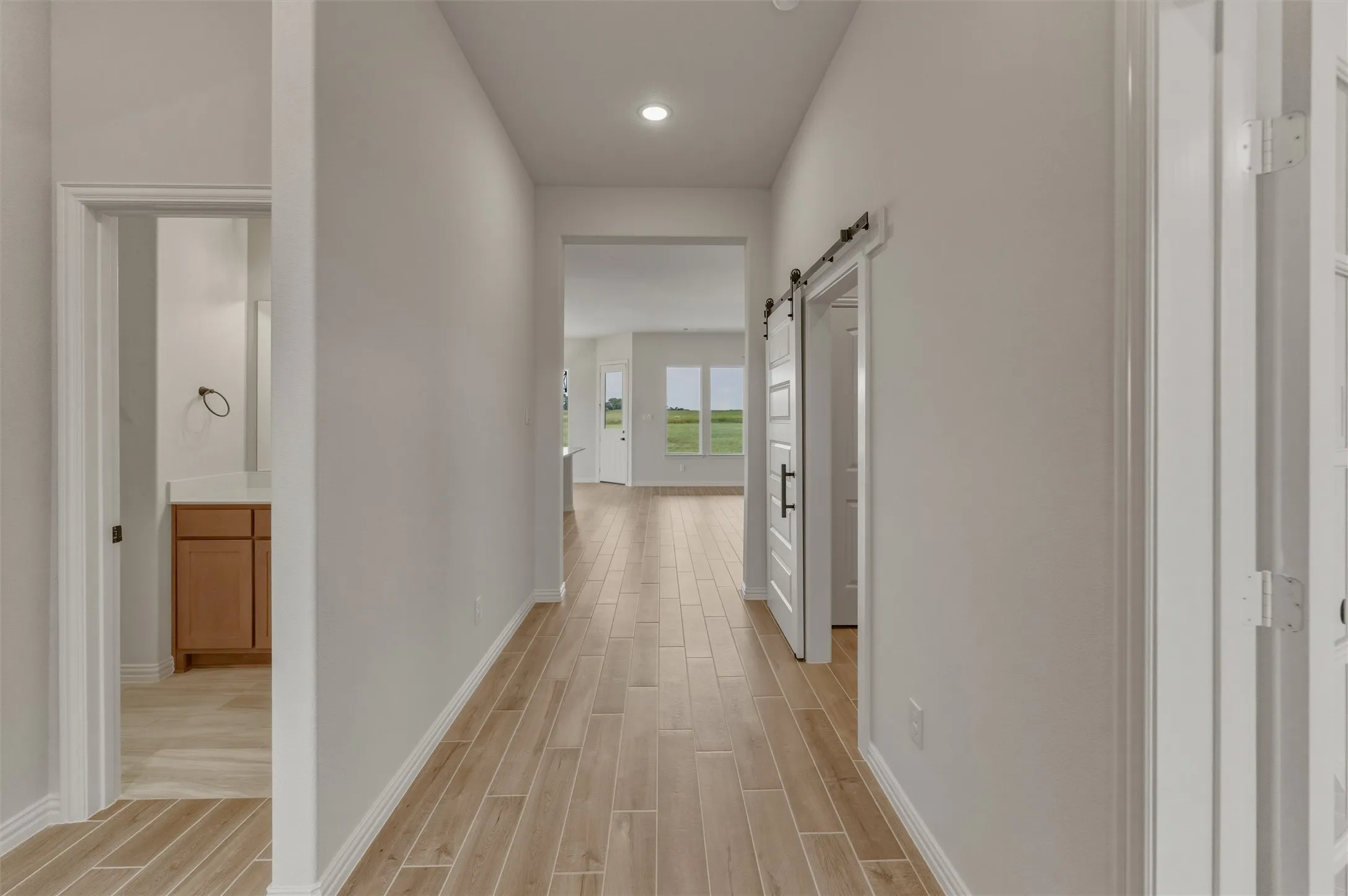 Hallway featuring wood-finish tile flooring, recessed lighting, and a white barn door