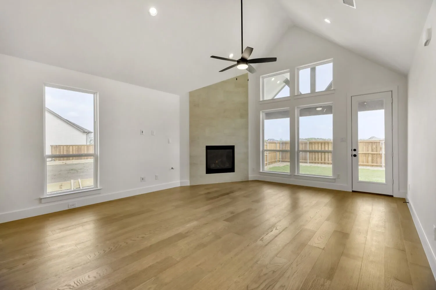 Unfurnished living room with a high ceiling, light wood-style flooring, a large fireplace, a ceiling fan, and recessed lighting