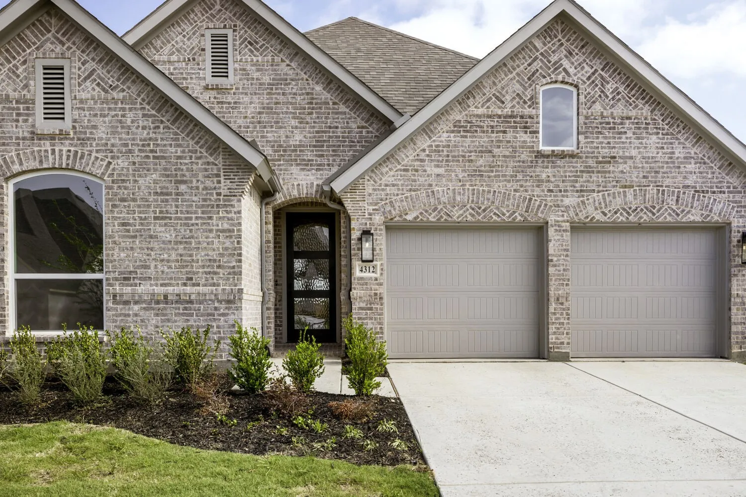 French country style house with driveway, brick siding, an attached garage, and a shingled roof