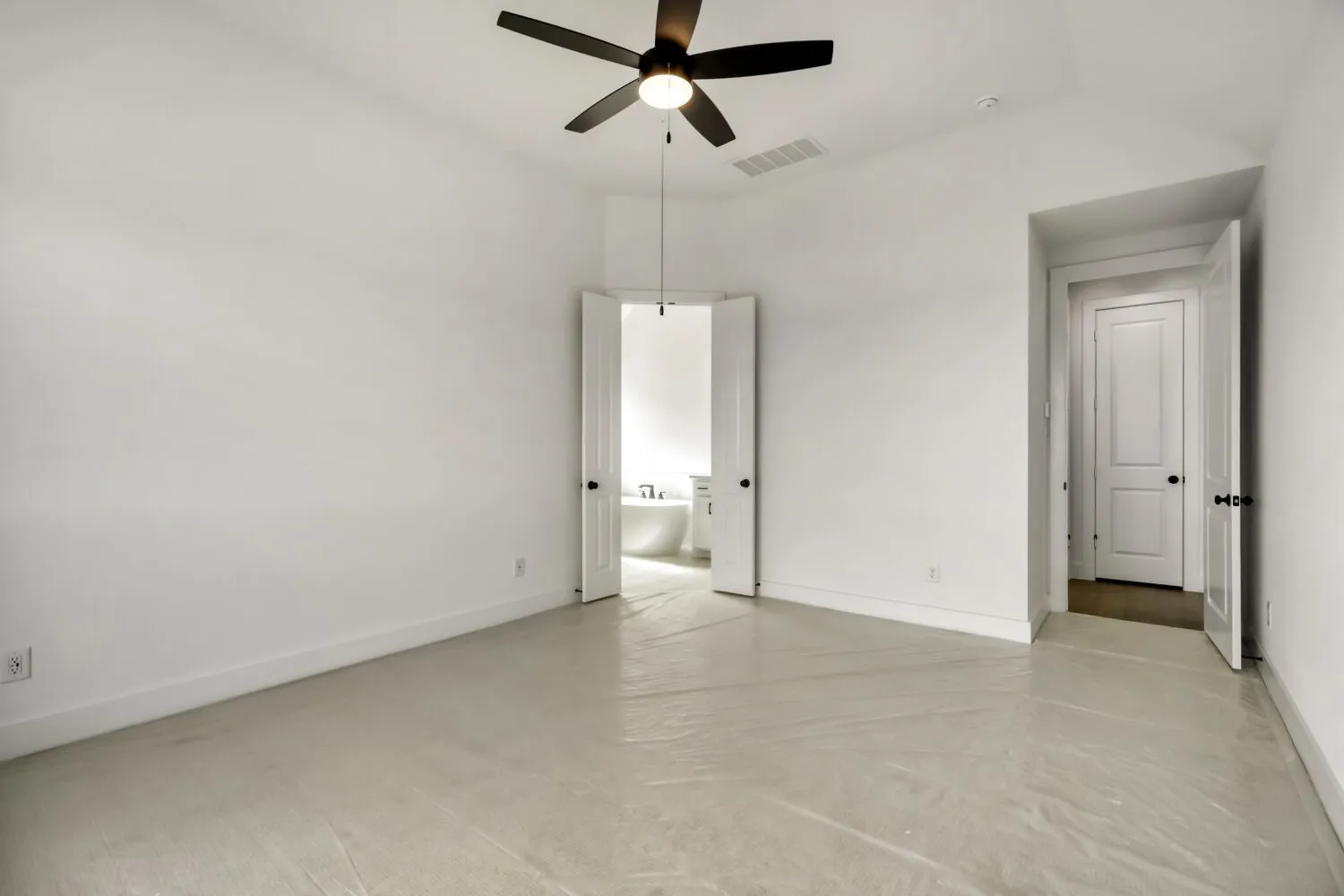 Unfurnished bedroom featuring concrete floors, a ceiling fan, ensuite bathroom, and lofted ceiling