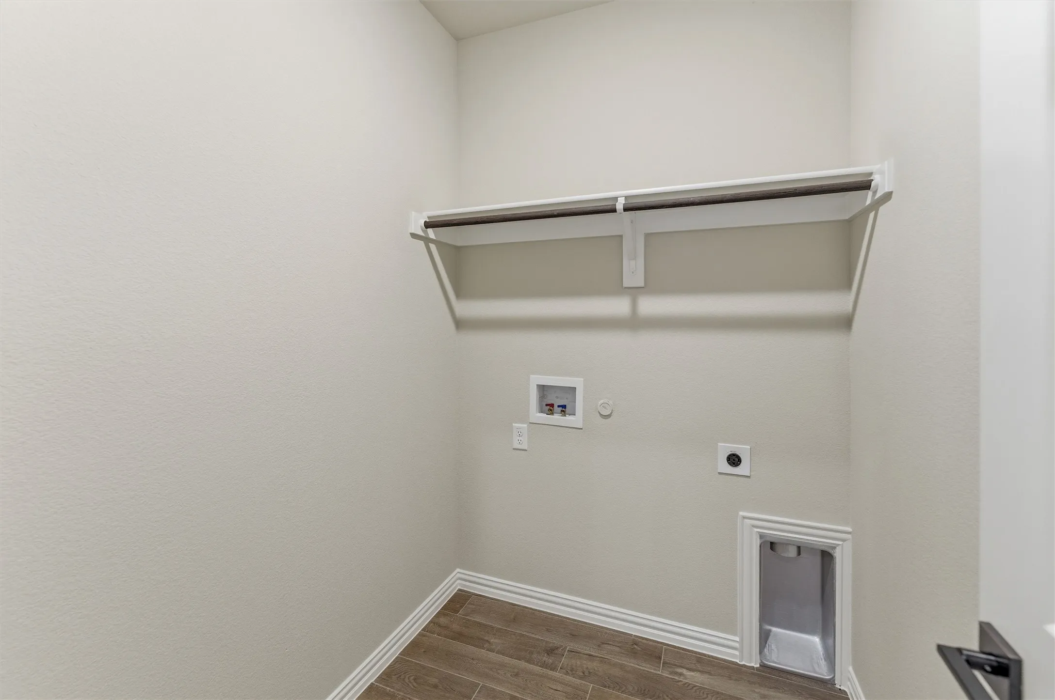 Dedicated utility space with wood-finish flooring, white baseboards, and light-toned walls