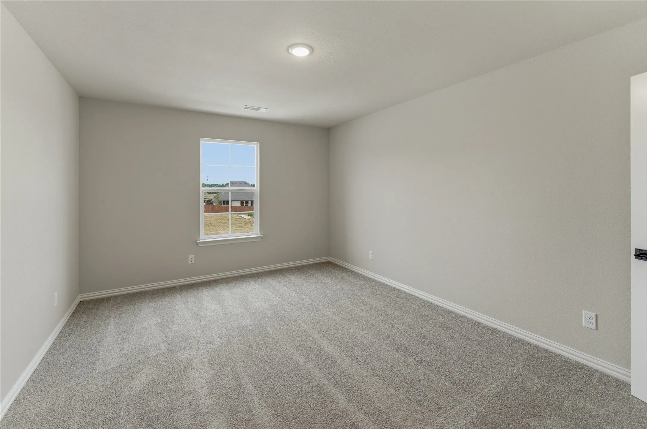 Neutral-toned interior room featuring light gray walls, gray carpet flooring, white baseboards, and a single window with white trim
