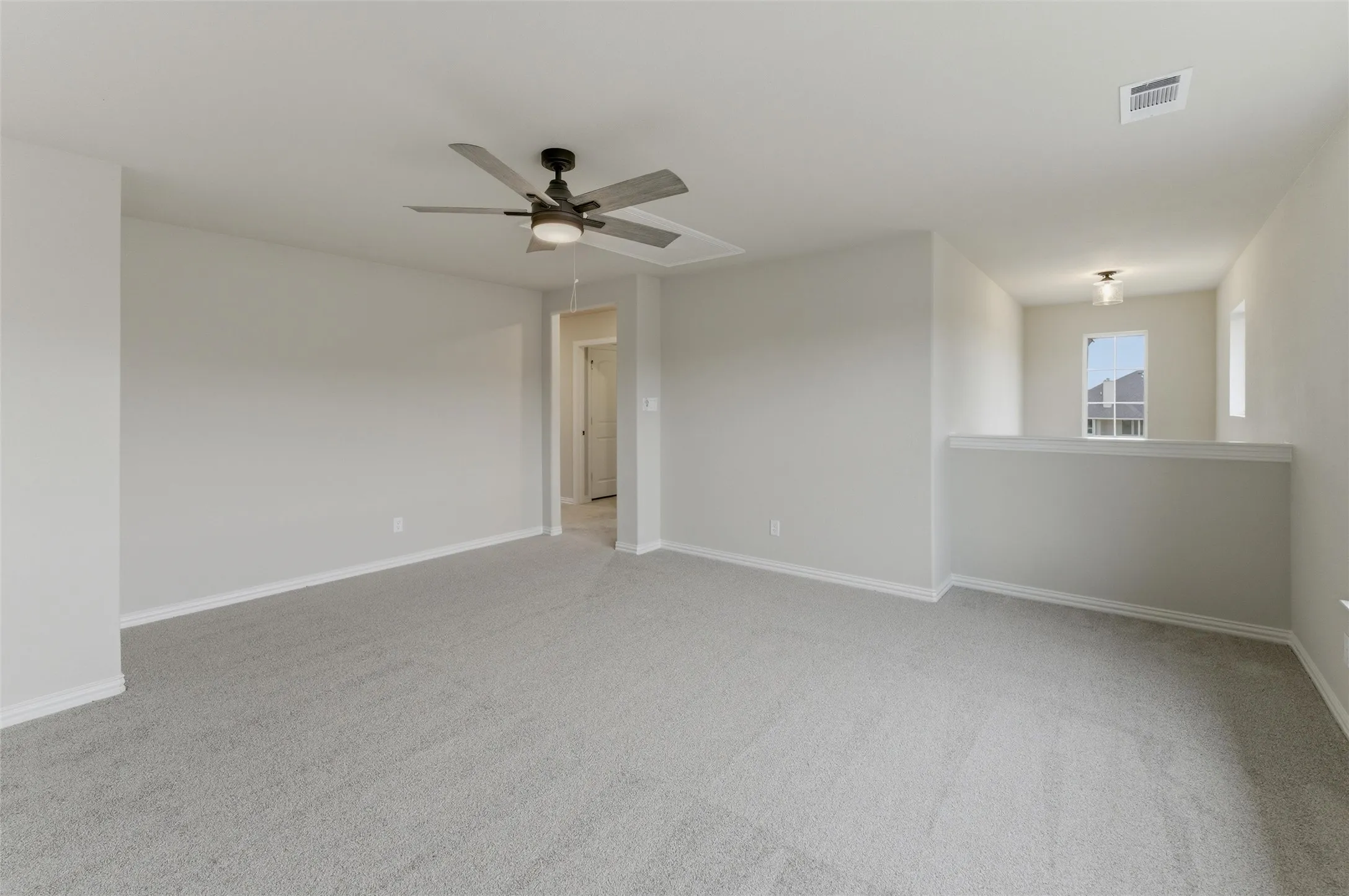 Spacious carpeted room featuring a ceiling fan with integrated lighting, neutral wall tones, and white trim