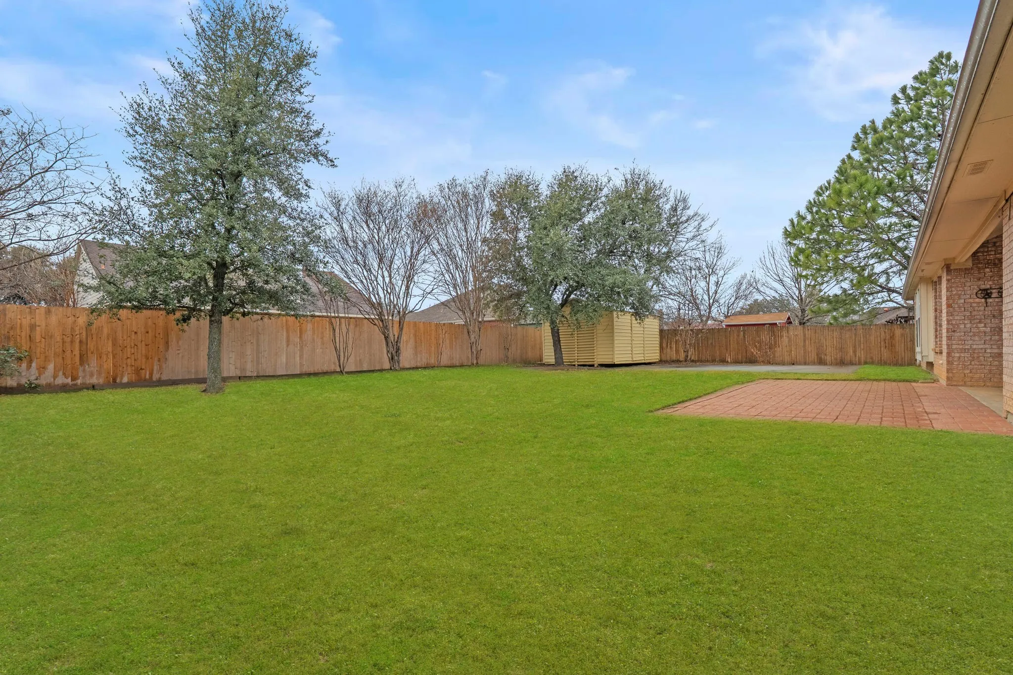 Fenced backyard with a storage unit and a patio area