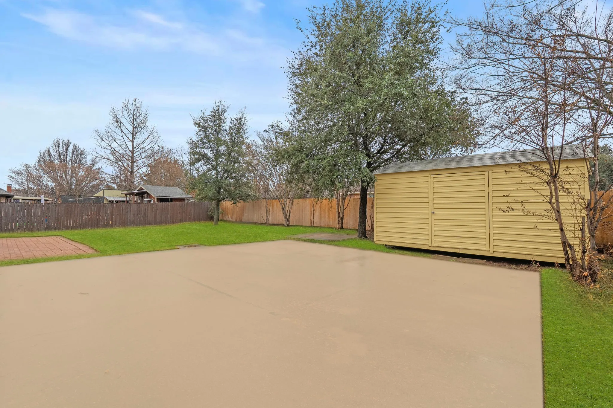 Fenced backyard featuring a shed