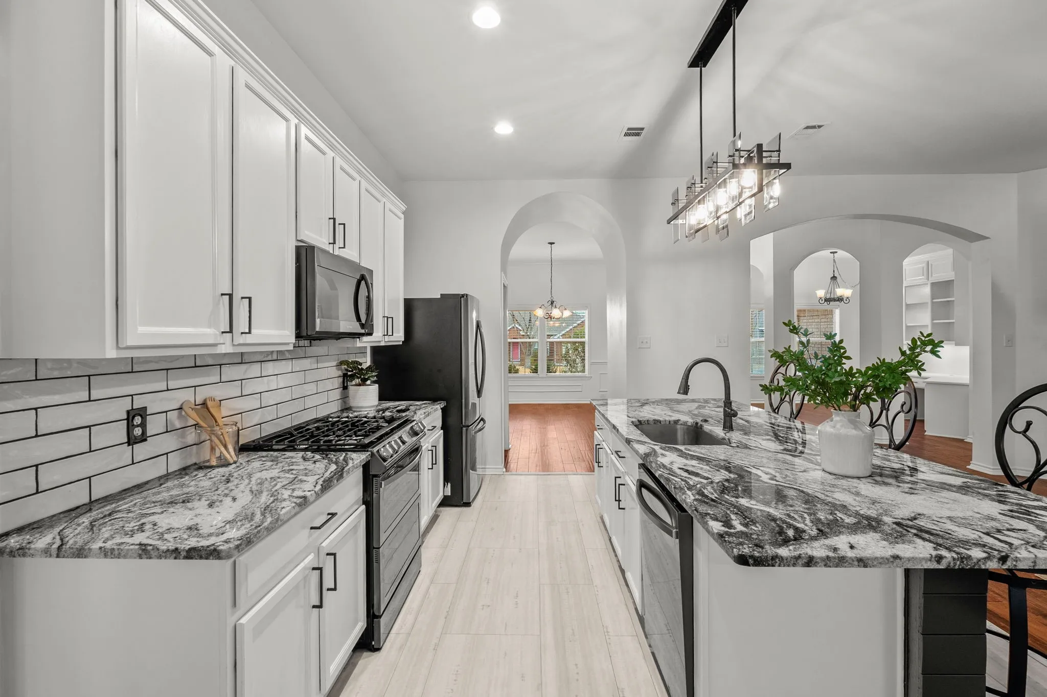 Kitchen featuring range with gas cooktop, dark stone countertops, white cabinets, a kitchen island with sink, and recessed lighting