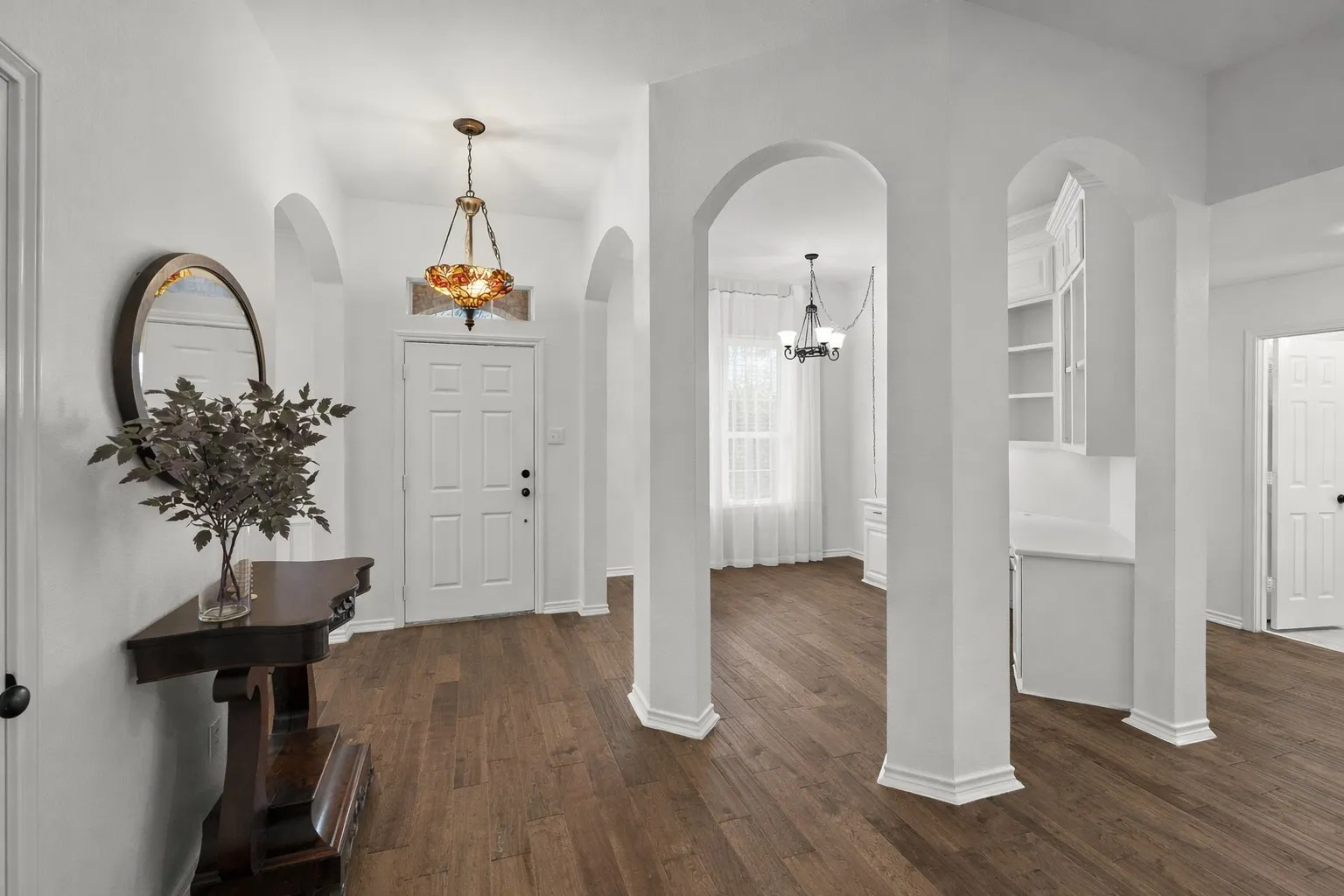 Entryway with dark wood finished floors, a chandelier, and arched walkways