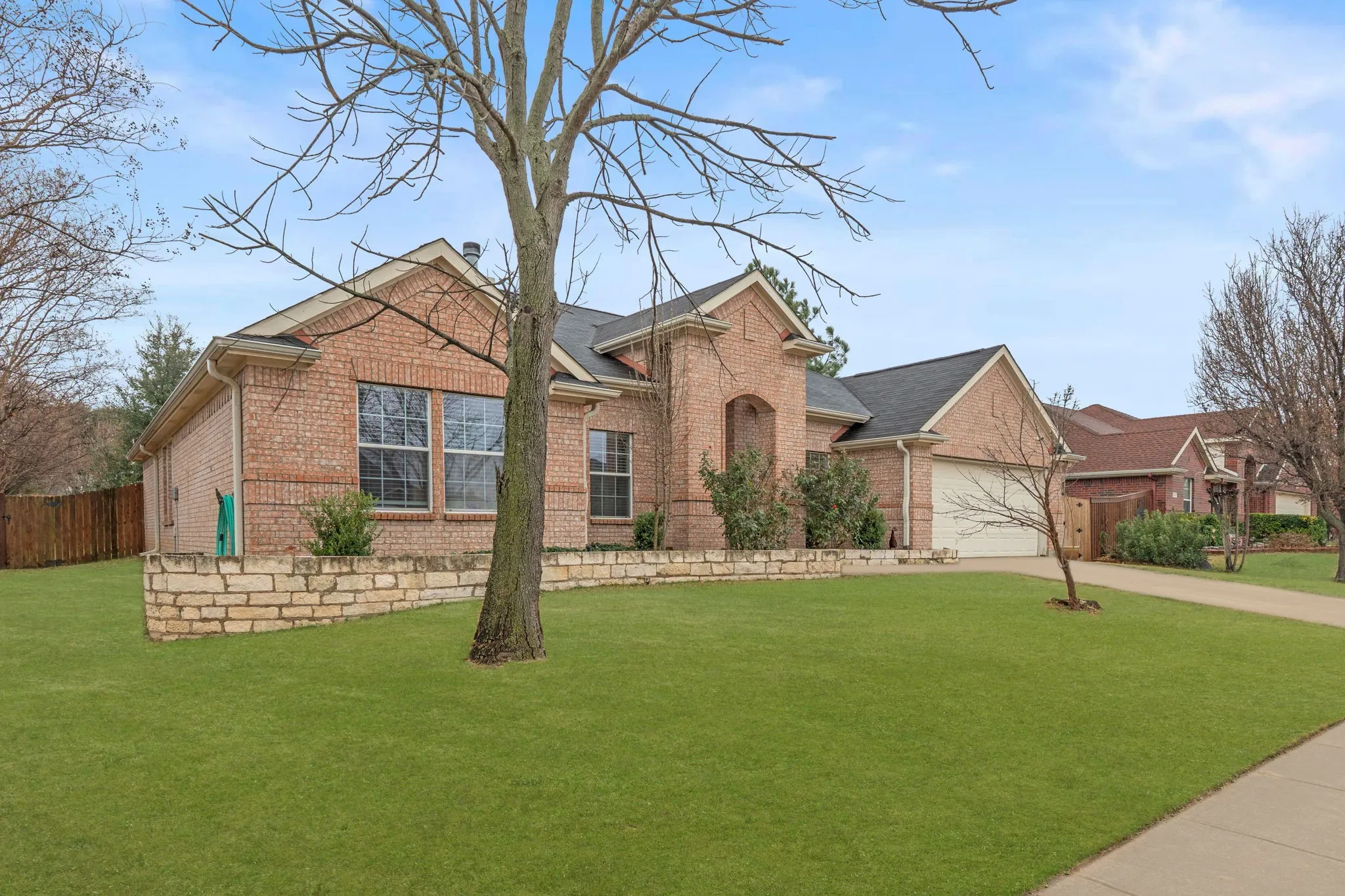 View of front facade with brick siding, driveway, and a garage