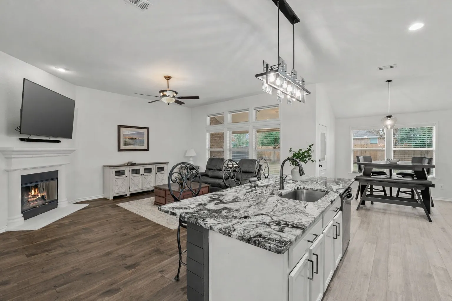 Kitchen featuring a kitchen bar, light stone counters, hanging light fixtures, open floor plan, and recessed lighting