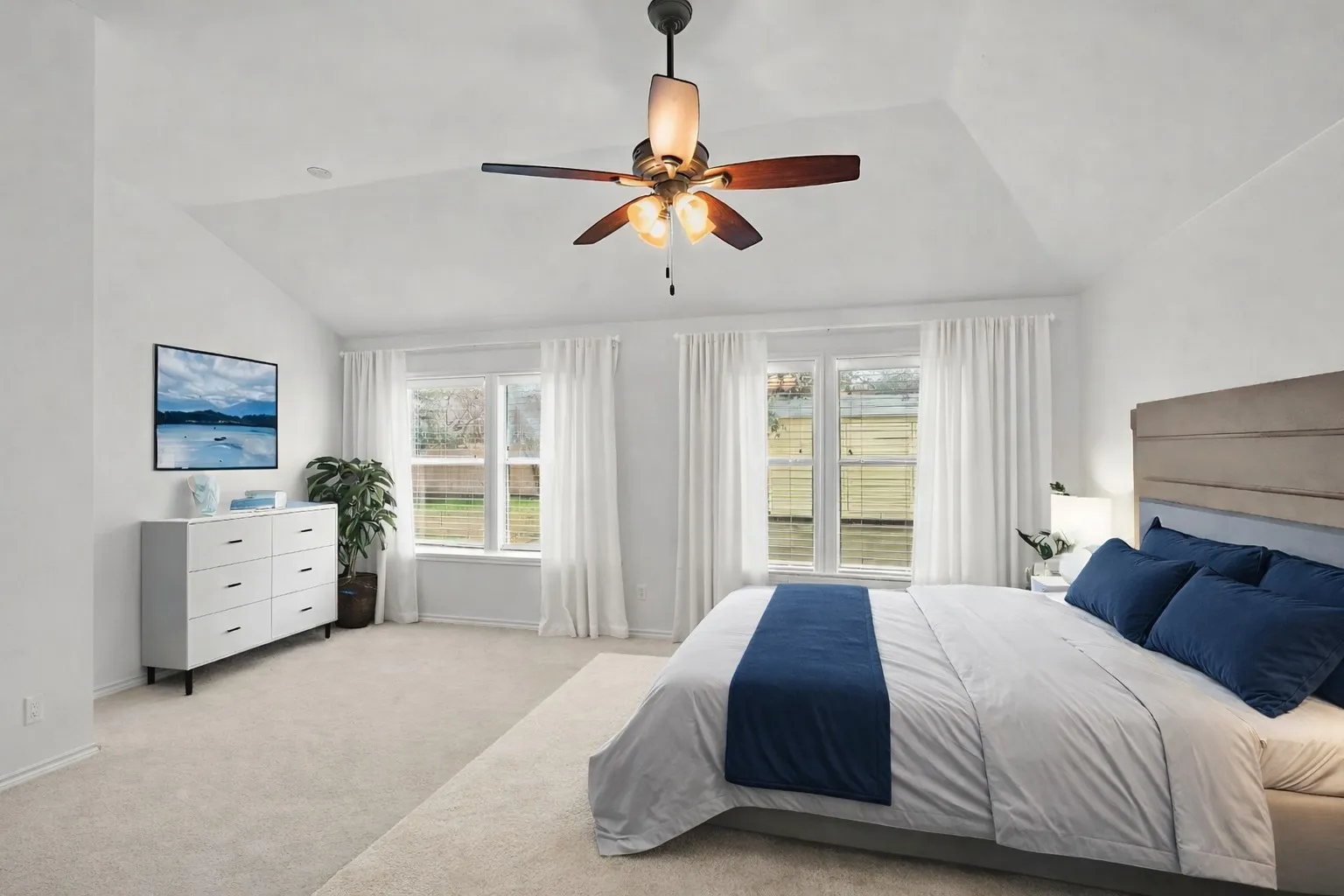 Bedroom featuring vaulted ceiling, carpet flooring, a ceiling fan, and multiple windows