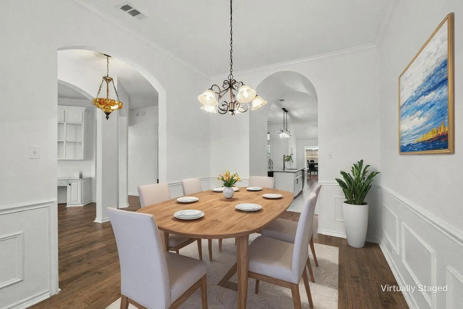Dining room with arched walkways, dark wood-style floors, a chandelier, a decorative wall, and a wainscoted wall