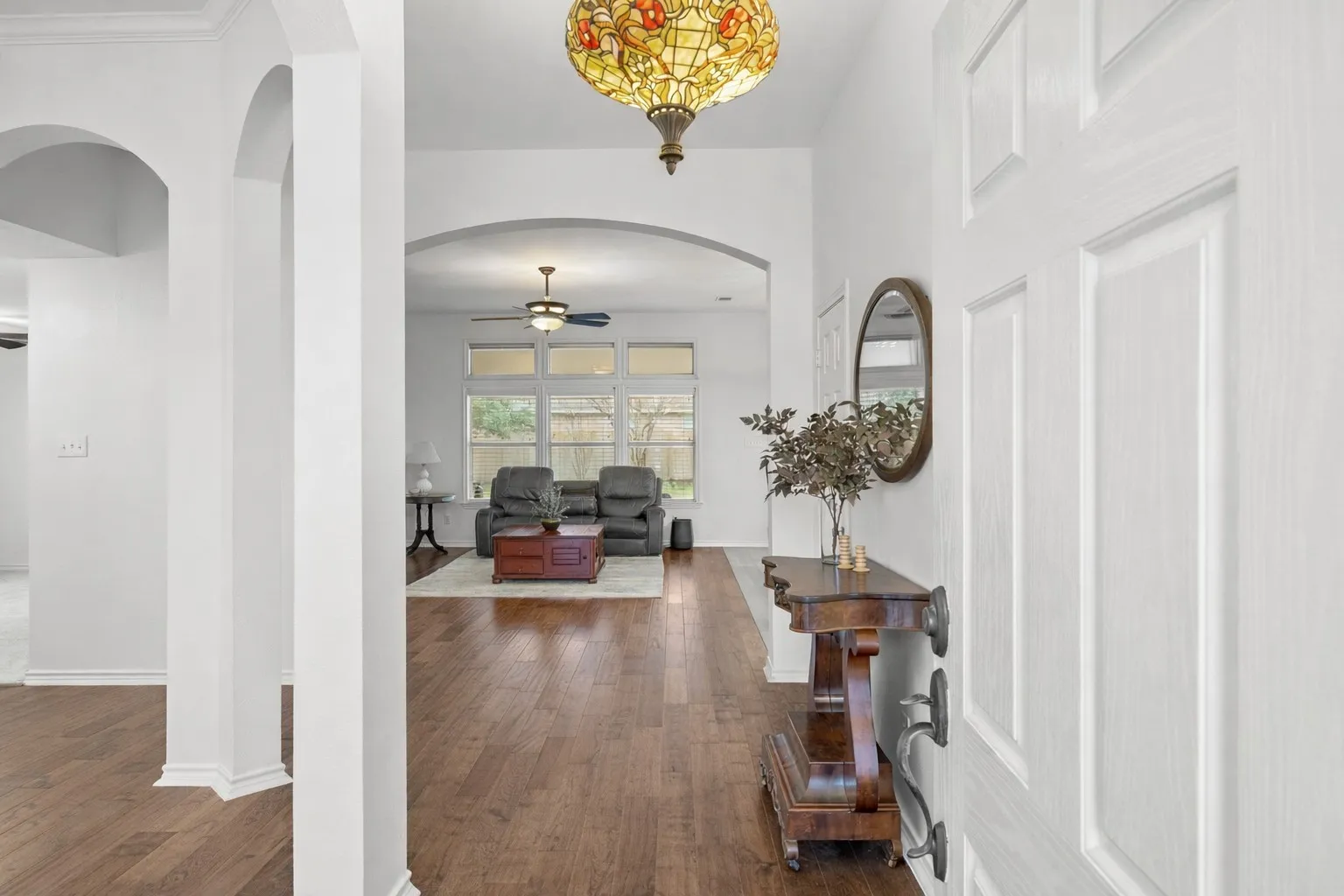 Entrance foyer with ceiling fan, arched walkways, and dark wood-style floors