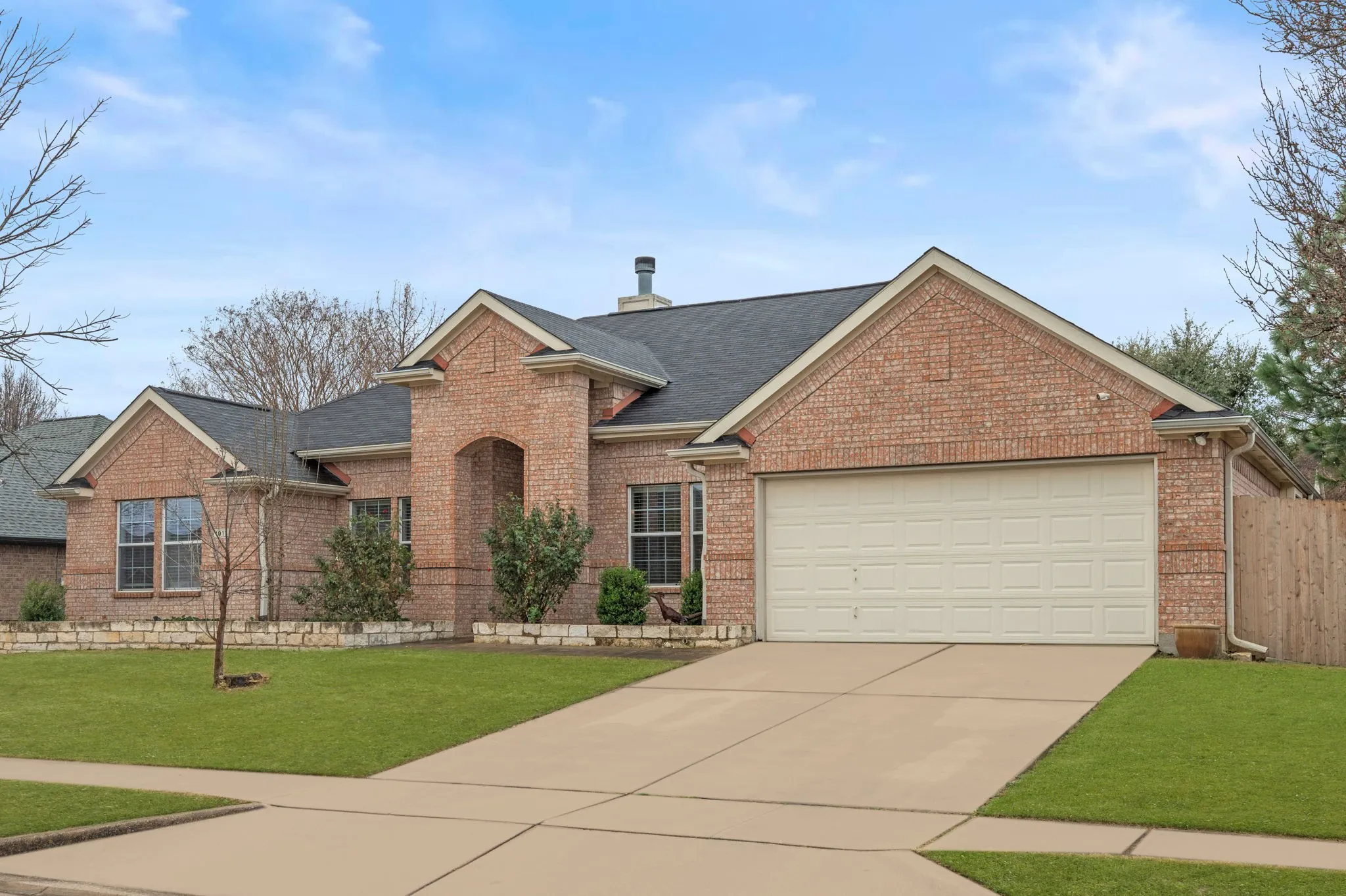 Traditional-style house with brick siding, driveway, roof with shingles, and a garage