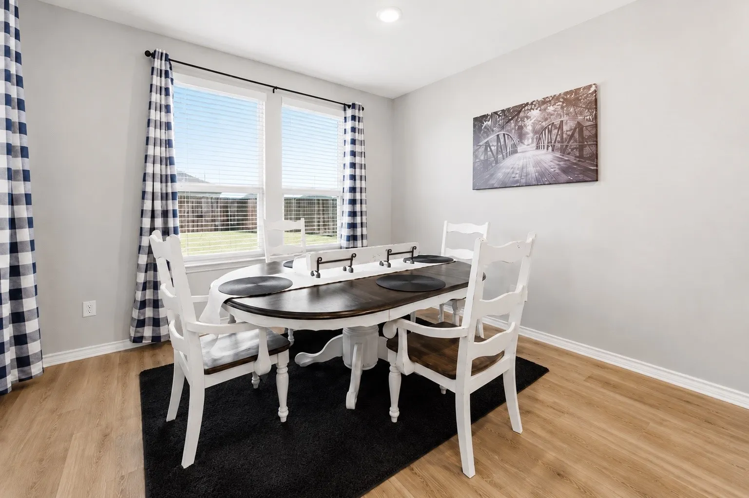 Brightly lit dining space featuring wood-finish flooring, light gray wall paint, and white trim
