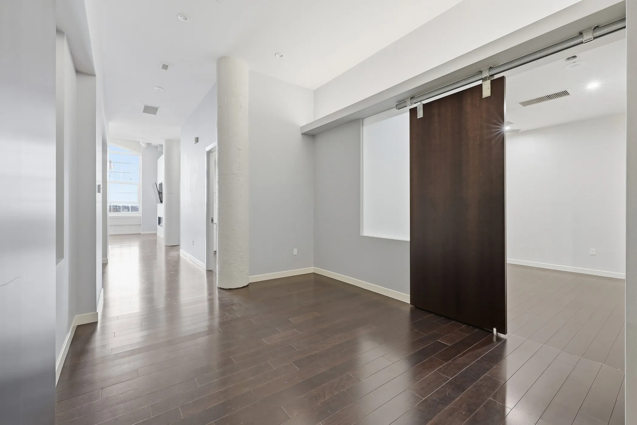Hall with a barn door and dark wood finished floors