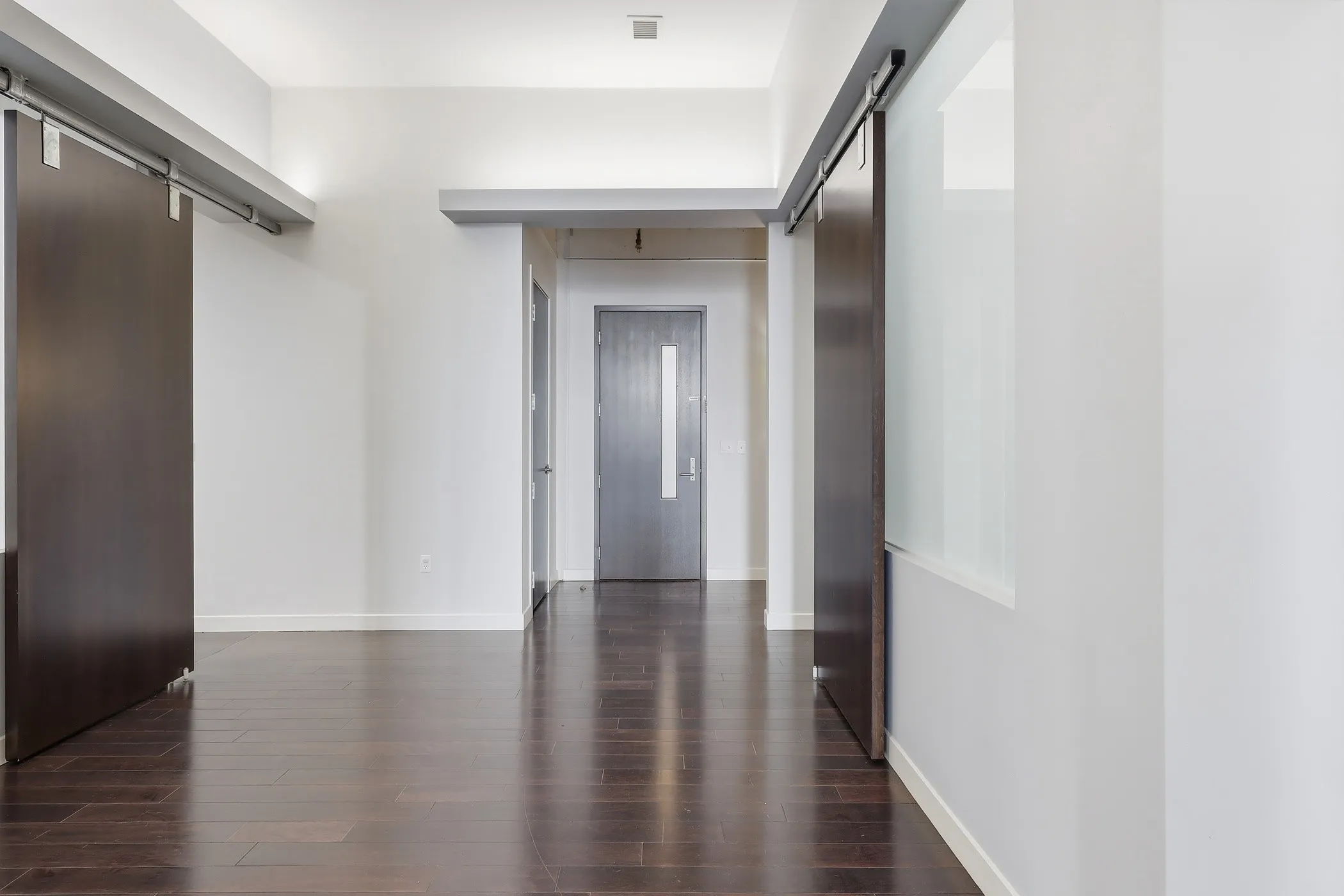 Walk in closet with a barn door and dark wood-style flooring