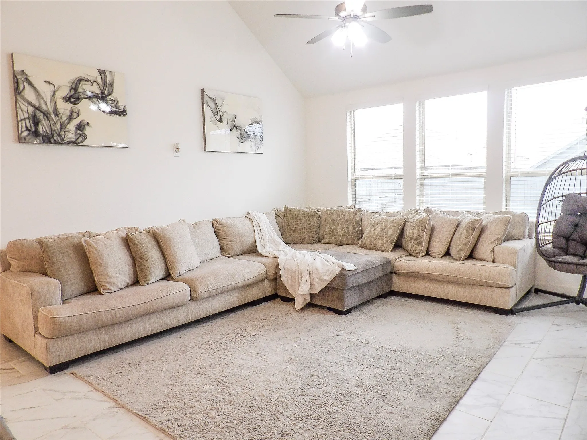 Living area with marble finish floors, lofted ceiling, and a ceiling fan