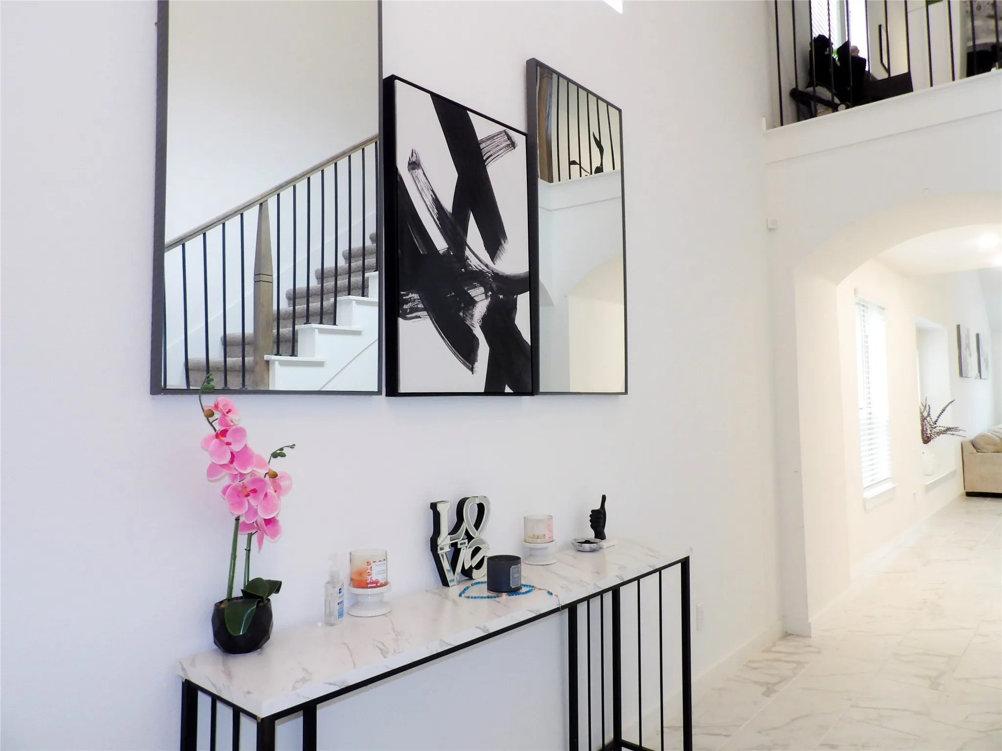 Hall featuring arched walkways, light marble finish floors, and a high ceiling