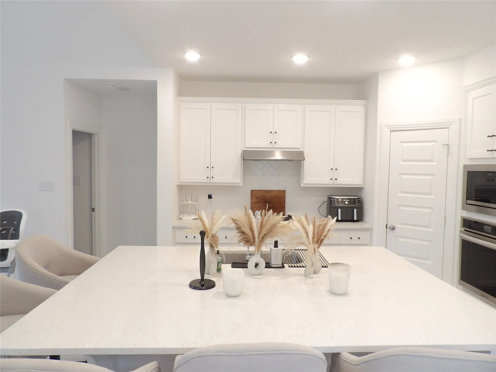 Kitchen with a breakfast bar area, white cabinets, light stone countertops, appliances with stainless steel finishes, and recessed lighting