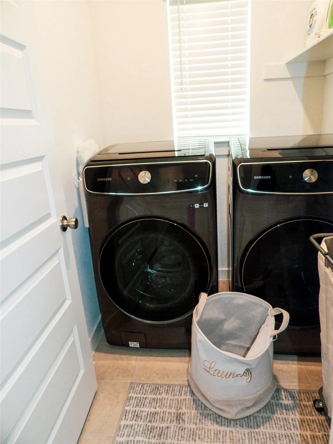 Laundry room with light tile patterned floors and washer and clothes dryer