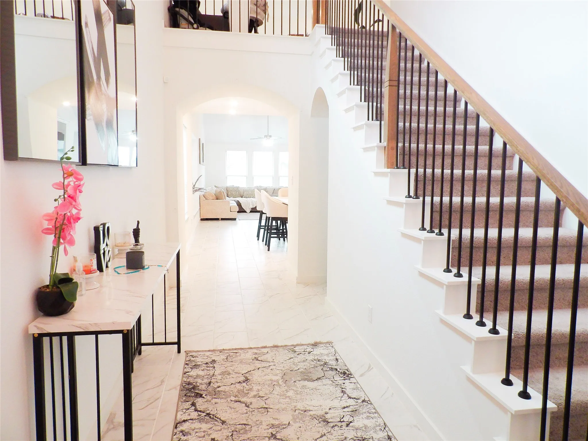Staircase with arched walkways, marble finish flooring, a high ceiling, and a ceiling fan
