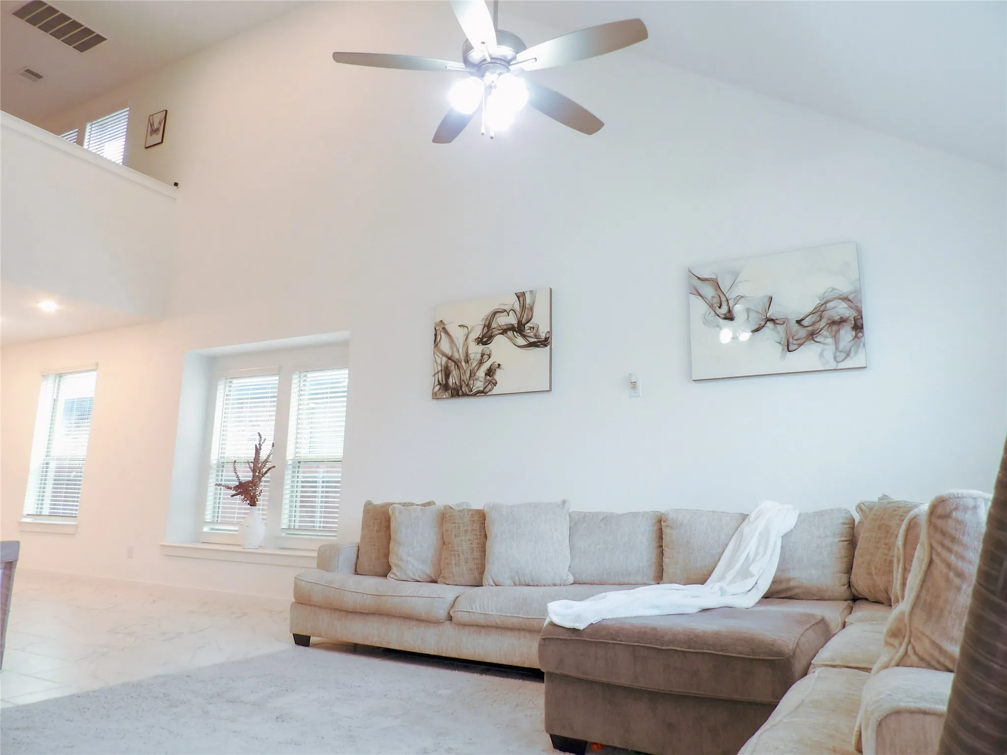 Carpeted living room featuring ceiling fan and high vaulted ceiling