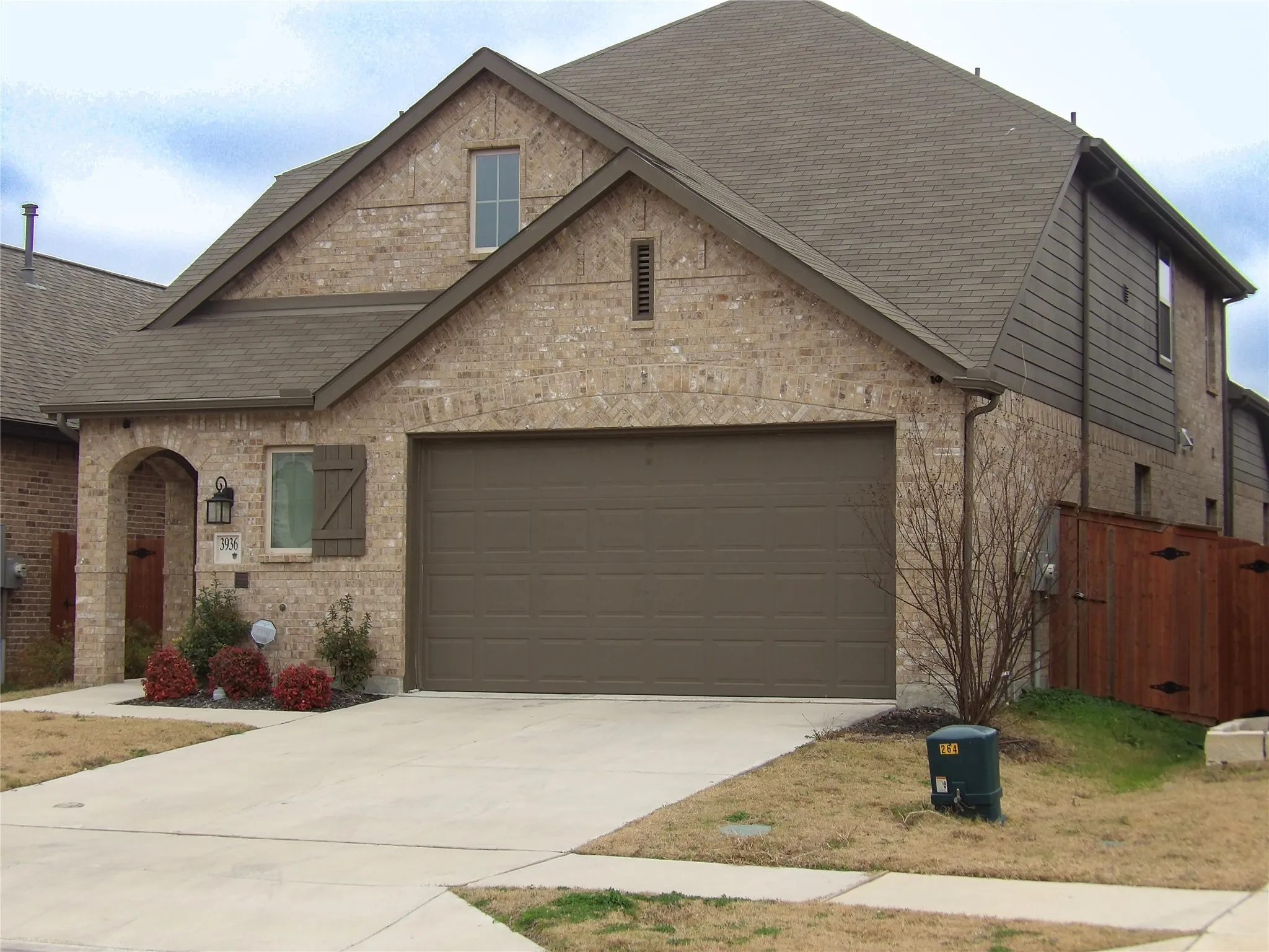 Front of home featuring a shingled roof, a garage, driveway, and brick siding