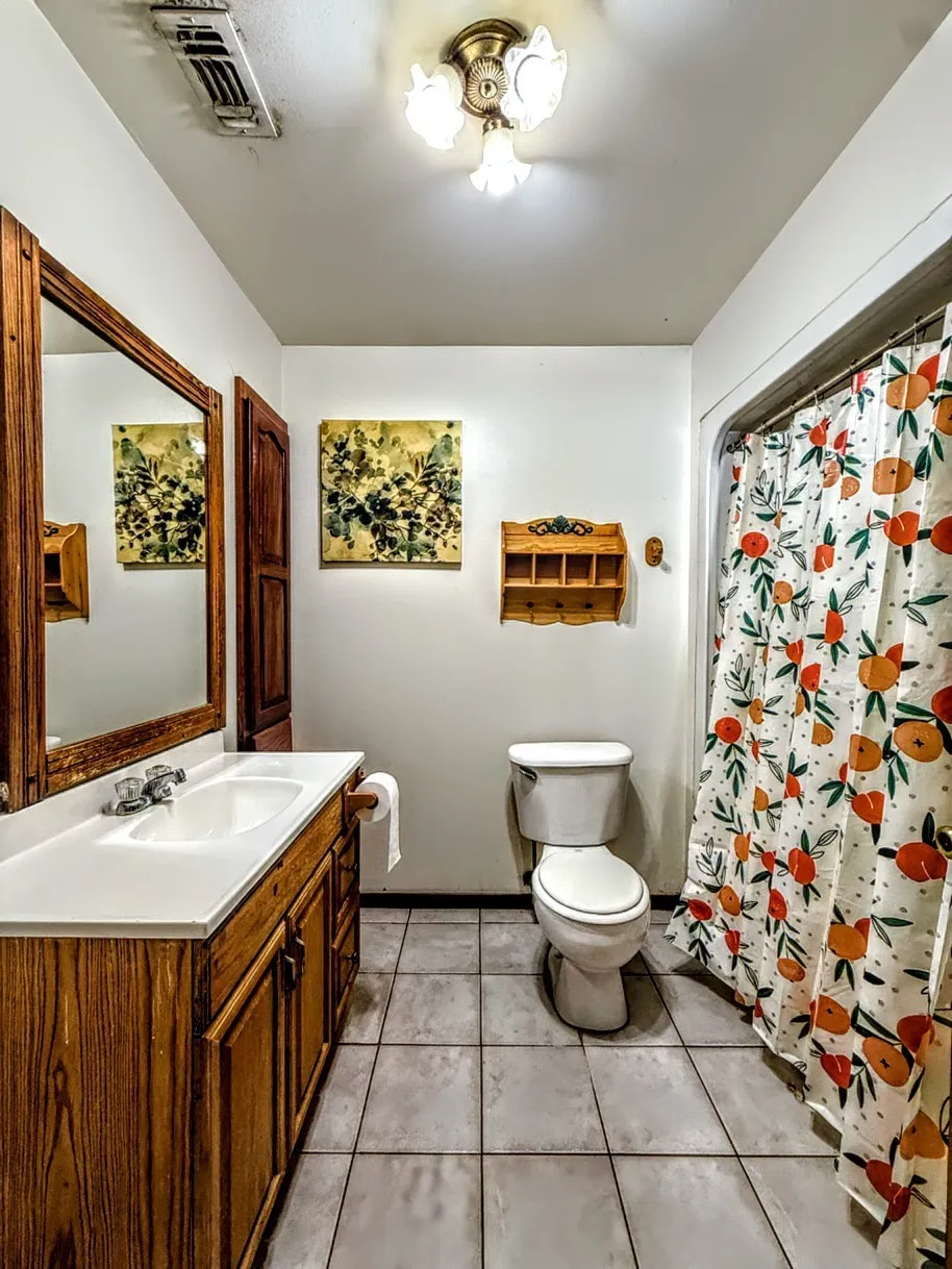 Full bath featuring a shower with curtain, vanity, and light tile patterned floors
