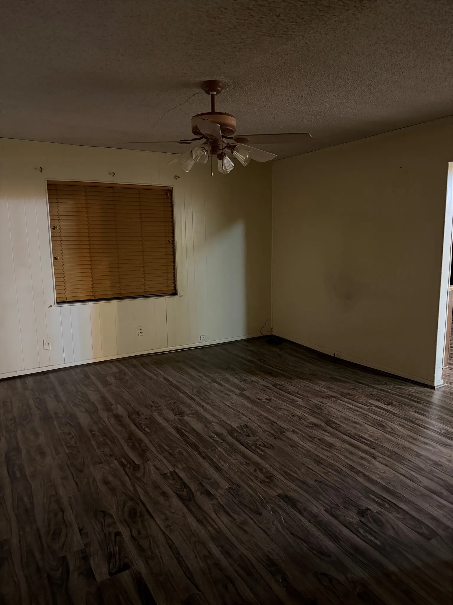 Empty room featuring dark wood-type flooring, a textured ceiling, and ceiling fan