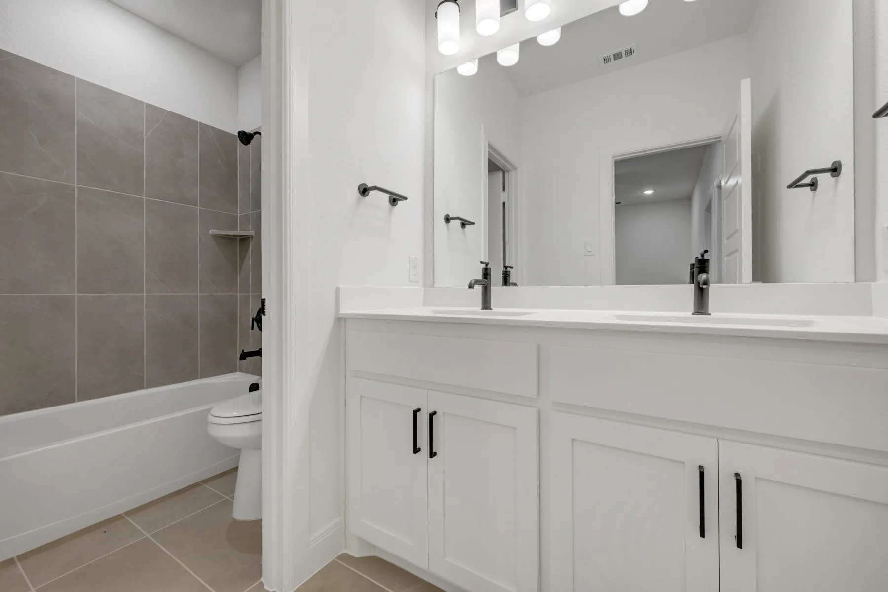 Bathroom featuring a dual vanity with white cabinetry, white countertops, and matte black fixtures