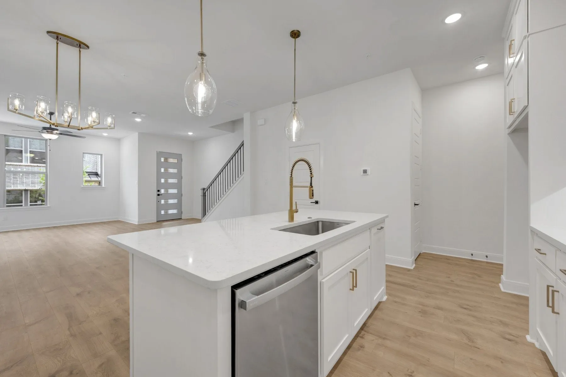Open-concept interior featuring a kitchen island with stone countertop, integrated sink, and stainless steel dishwasher