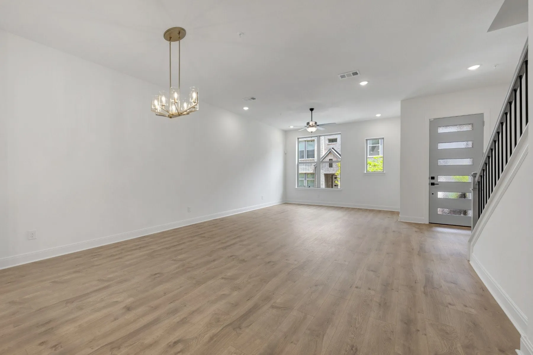 Open-concept living space featuring wood-finish flooring, recessed lighting, and a contemporary chandelier