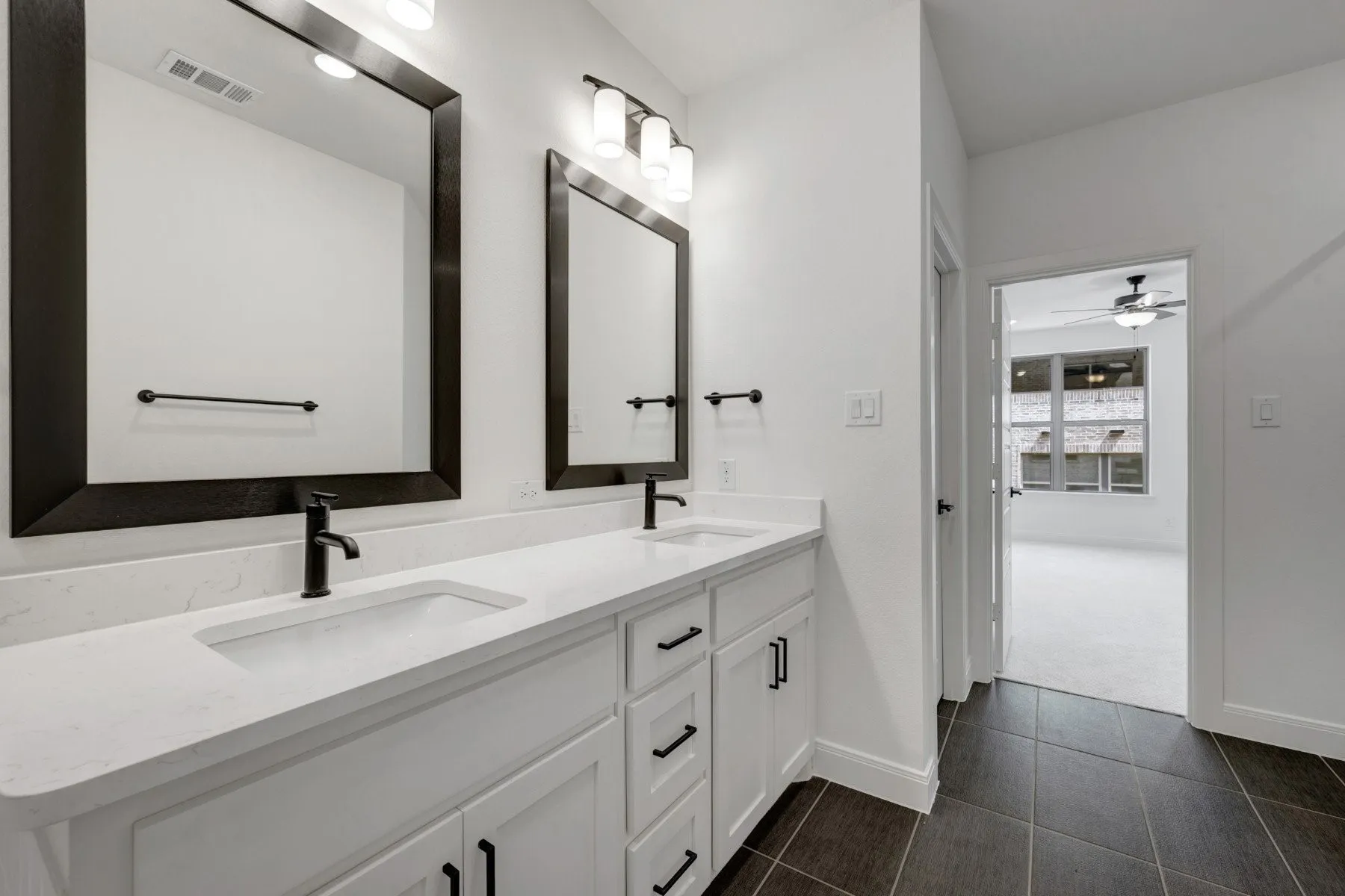Dual vanity featuring white countertops, integrated sinks, and black hardware