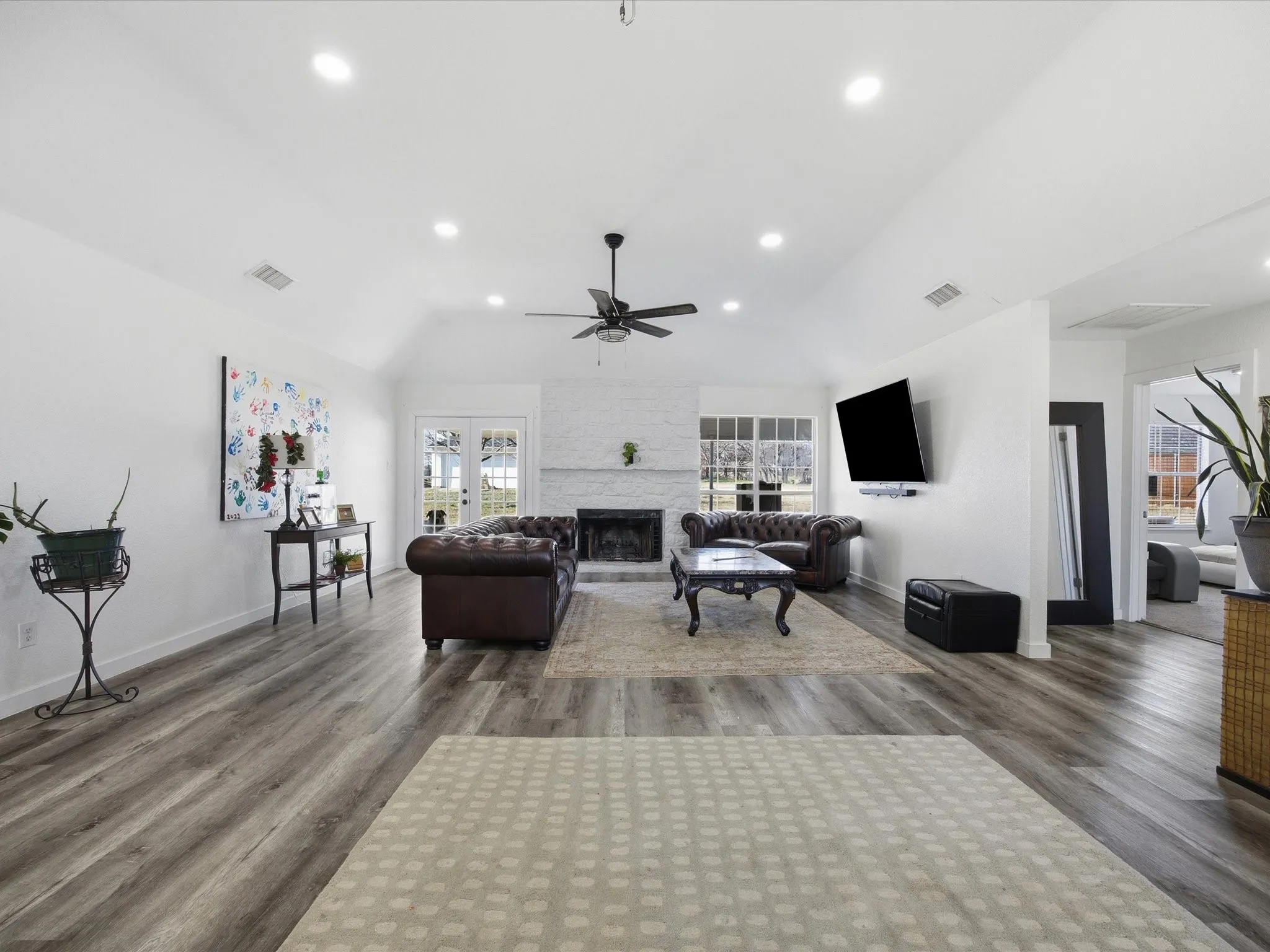 Living room featuring dark wood-style floors, a stone fireplace, lofted ceiling, recessed lighting, and ceiling fan