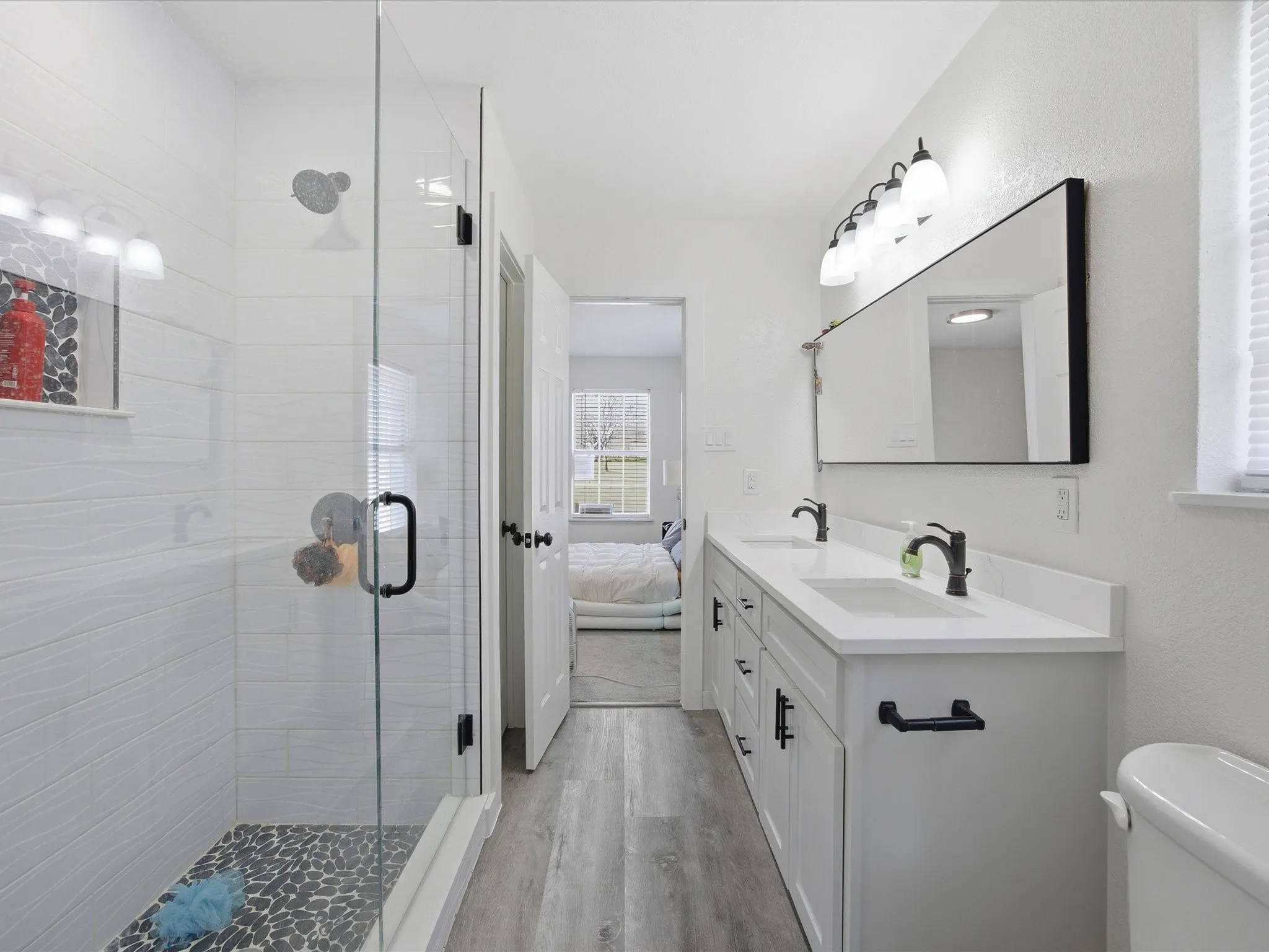 Bathroom featuring a stall shower, double vanity, light wood finished floors, and ensuite bath