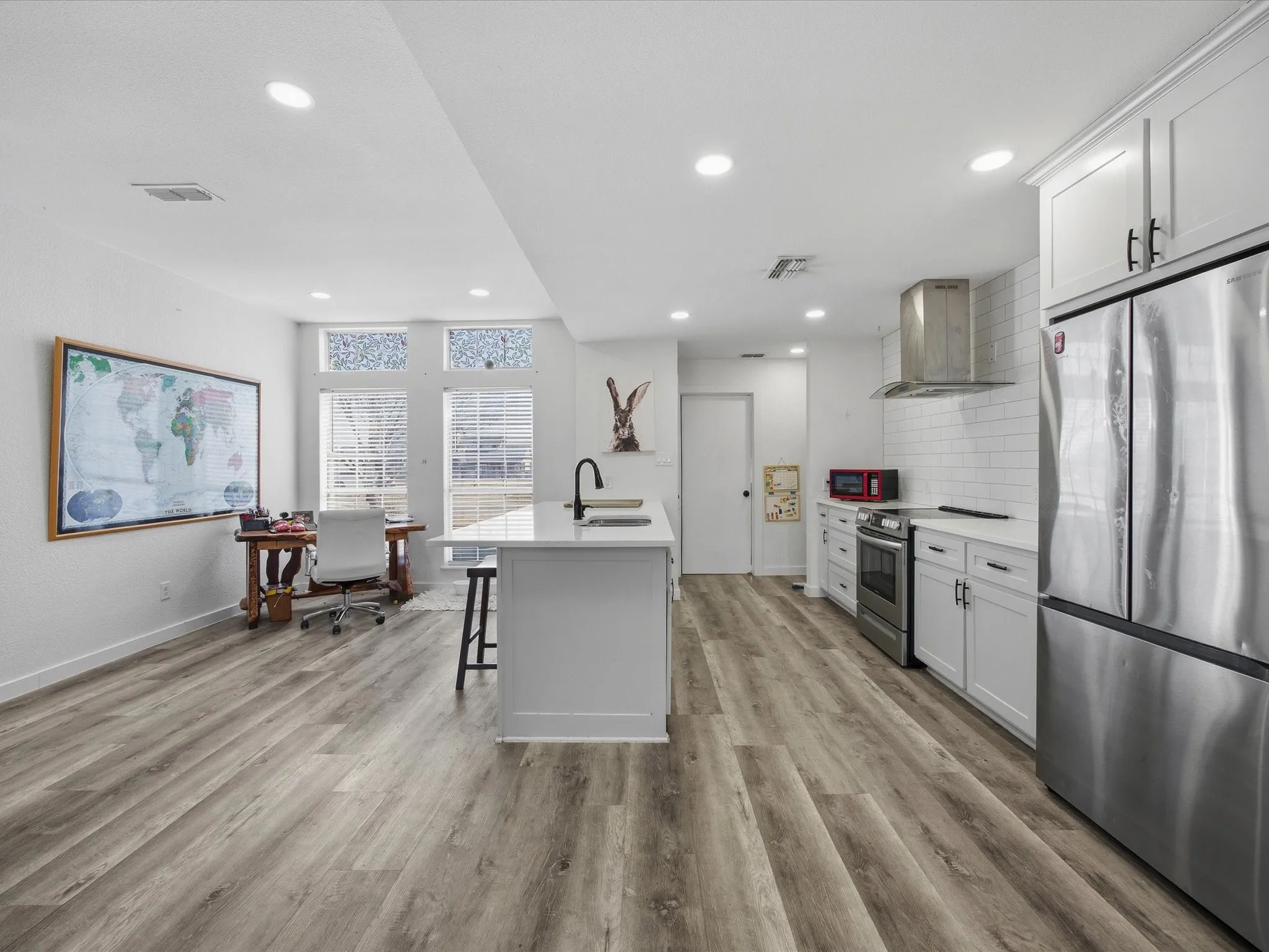 Kitchen featuring appliances with stainless steel finishes, extractor fan, white cabinets, a desk, and a breakfast bar area