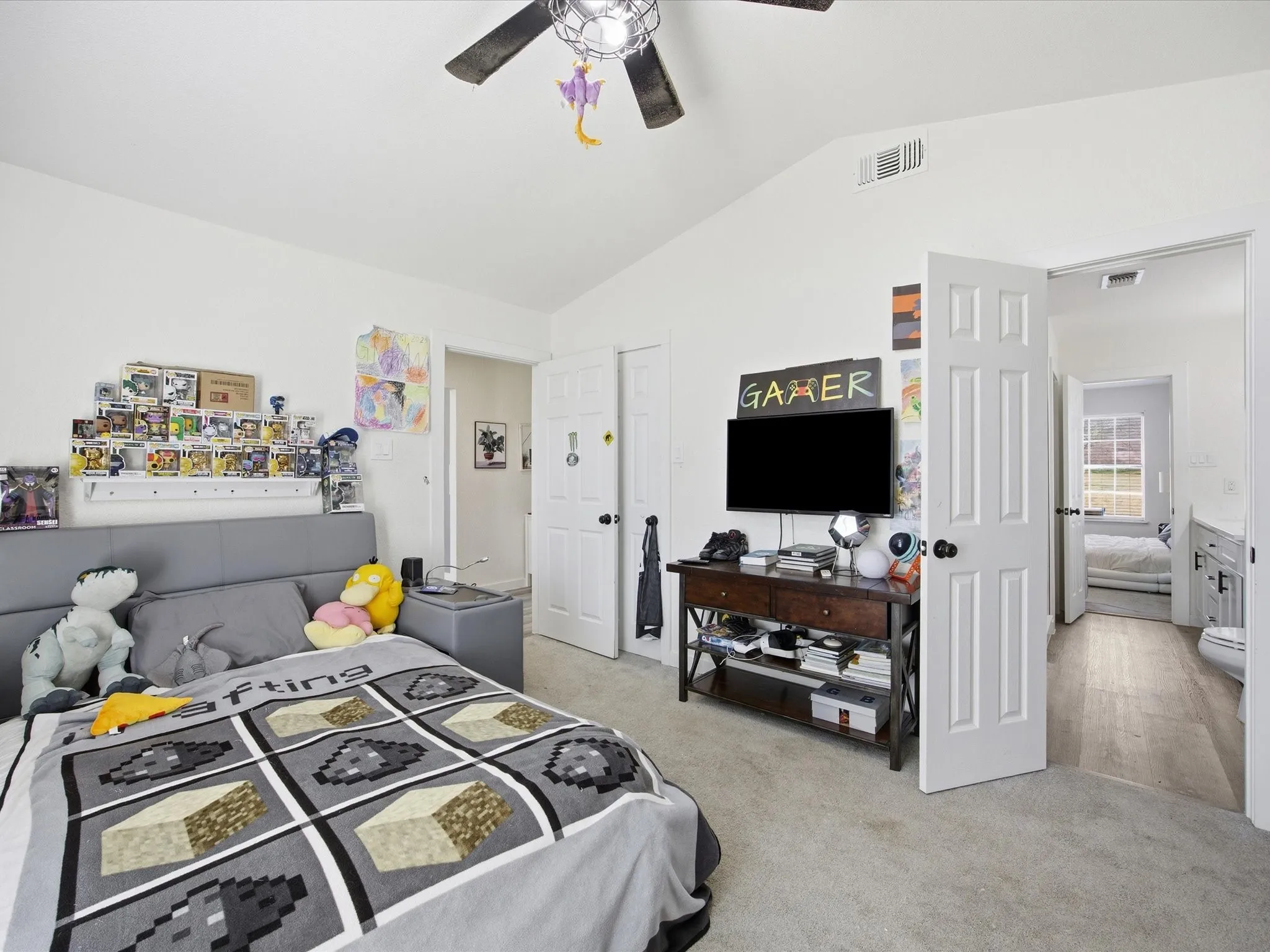 Bedroom with vaulted ceiling, a ceiling fan, and light carpet