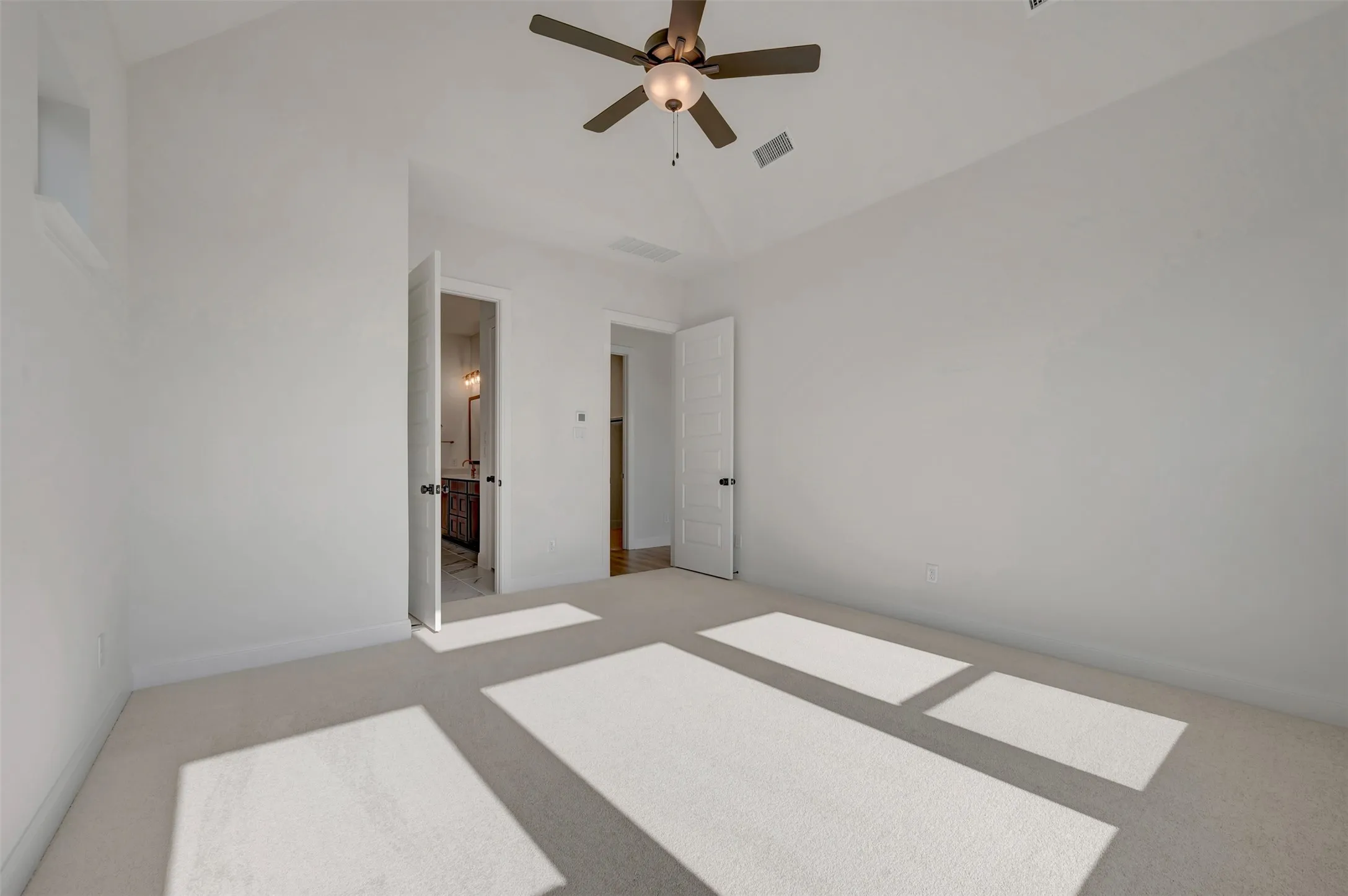 Carpeted room with a vaulted ceiling and a ceiling fan
