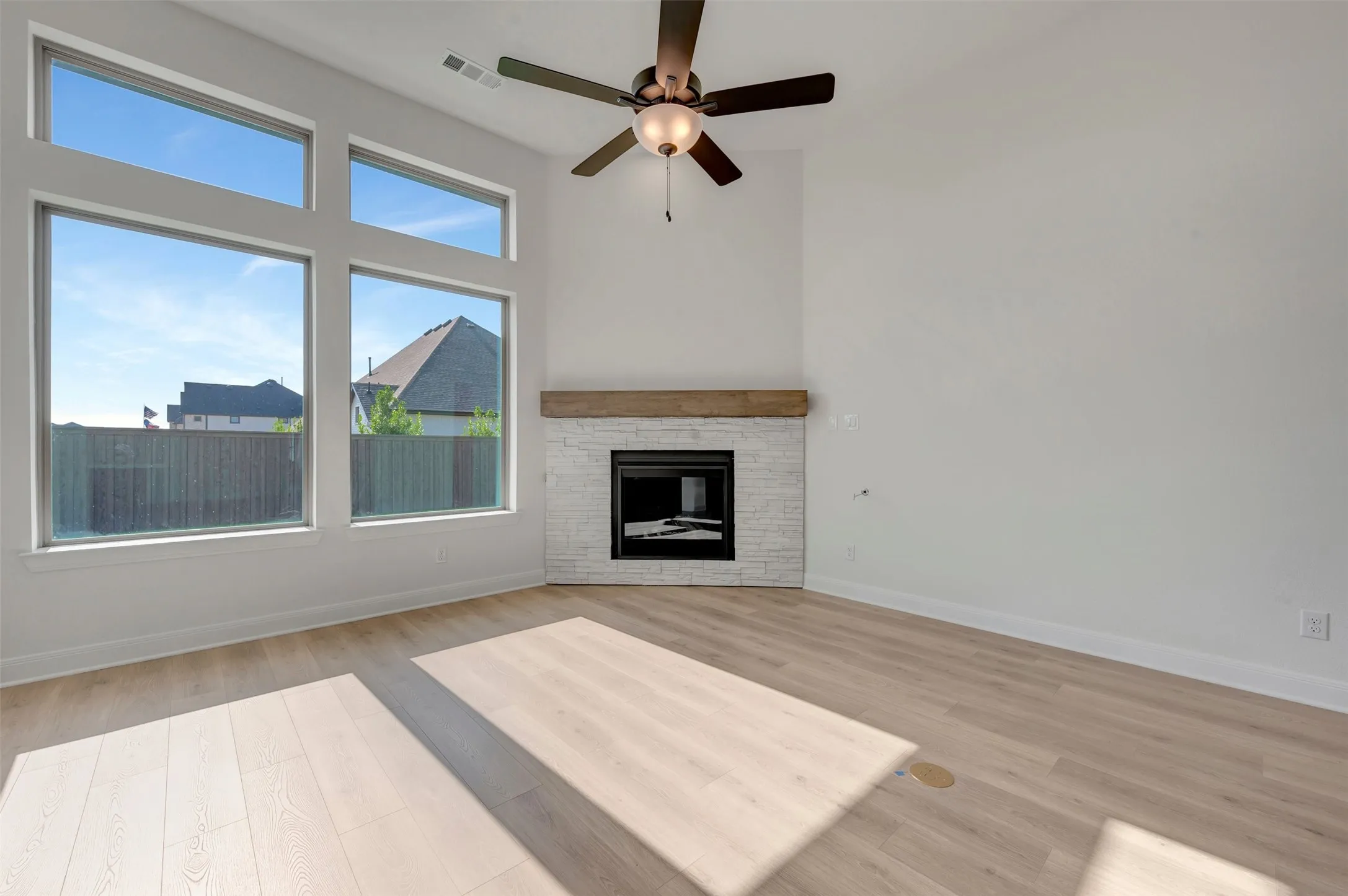 Spacious room featuring wood-finish flooring and a white brick fireplace with a wood mantel
