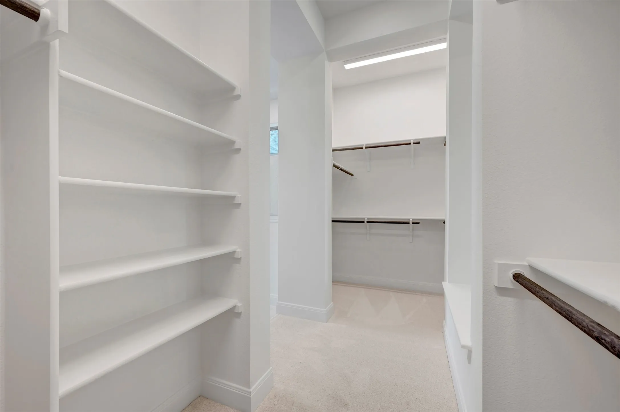 Expansive walk-in closet featuring built-in shelving, multiple hanging rods, recessed lighting, and soft carpet flooring