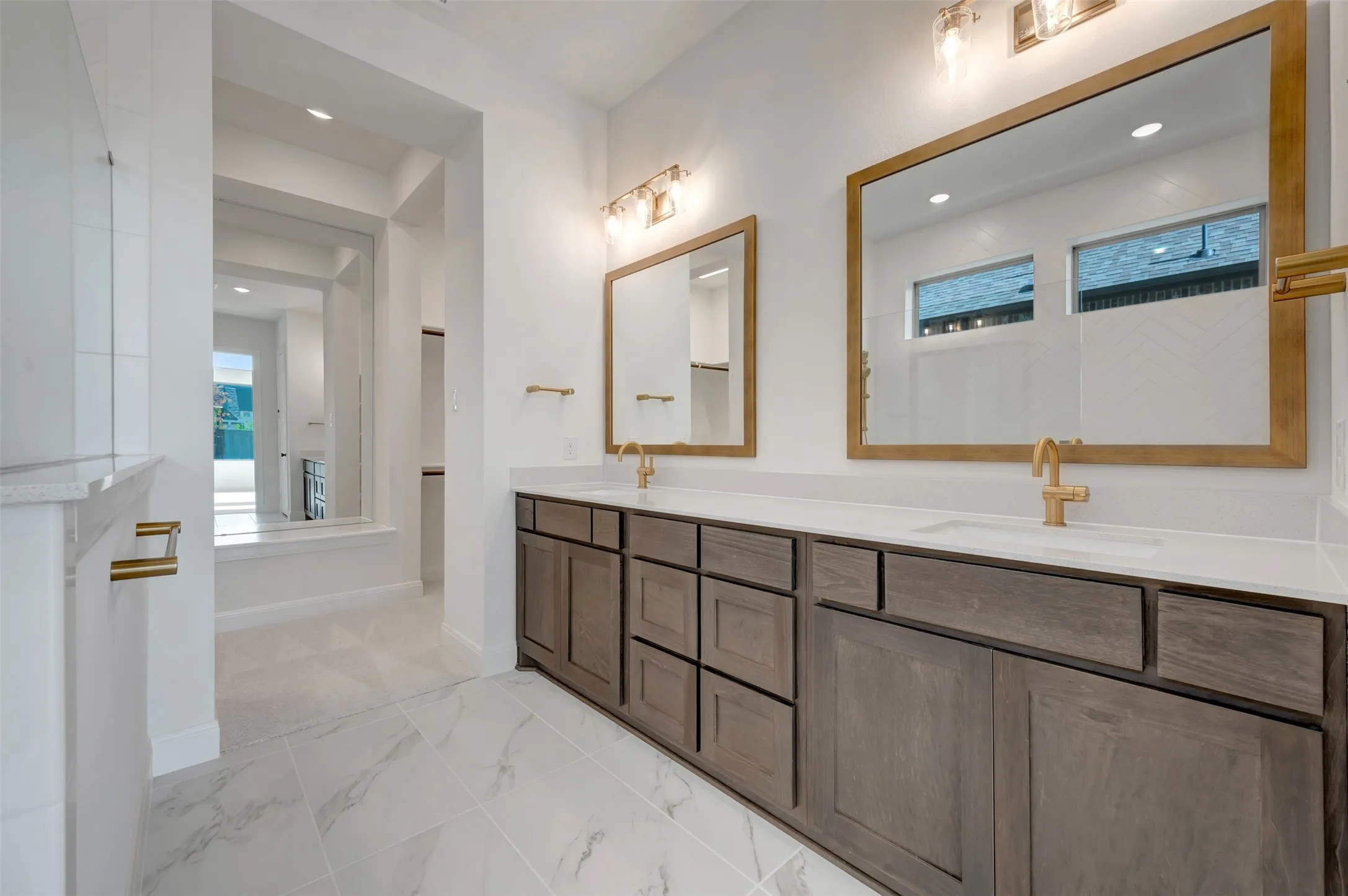Double vanity featuring dark wood-finish cabinetry, white countertops, and gold-toned fixtures
