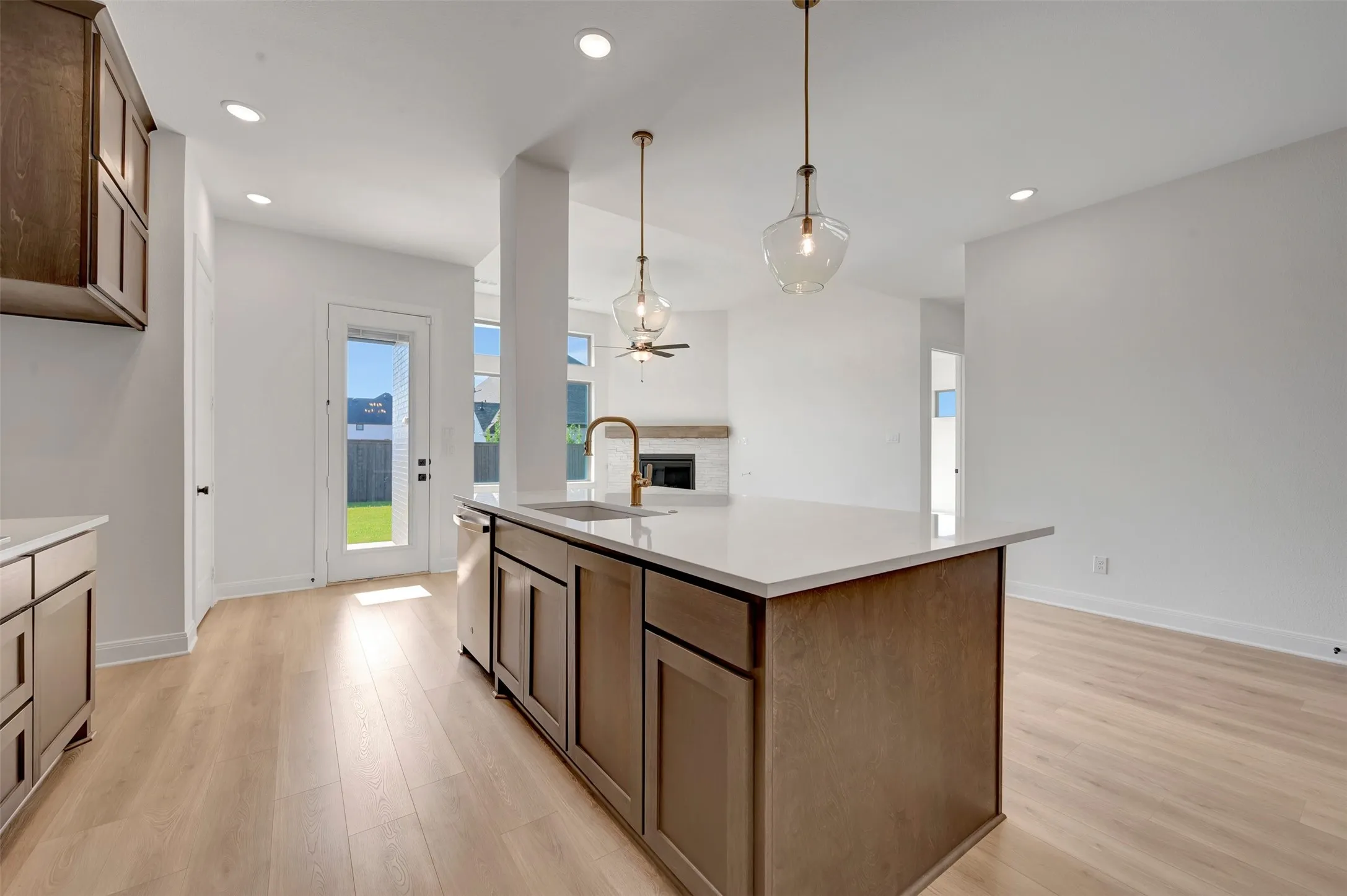 Kitchen island with a light-toned countertop and integrated sink featuring a gold-finish faucet