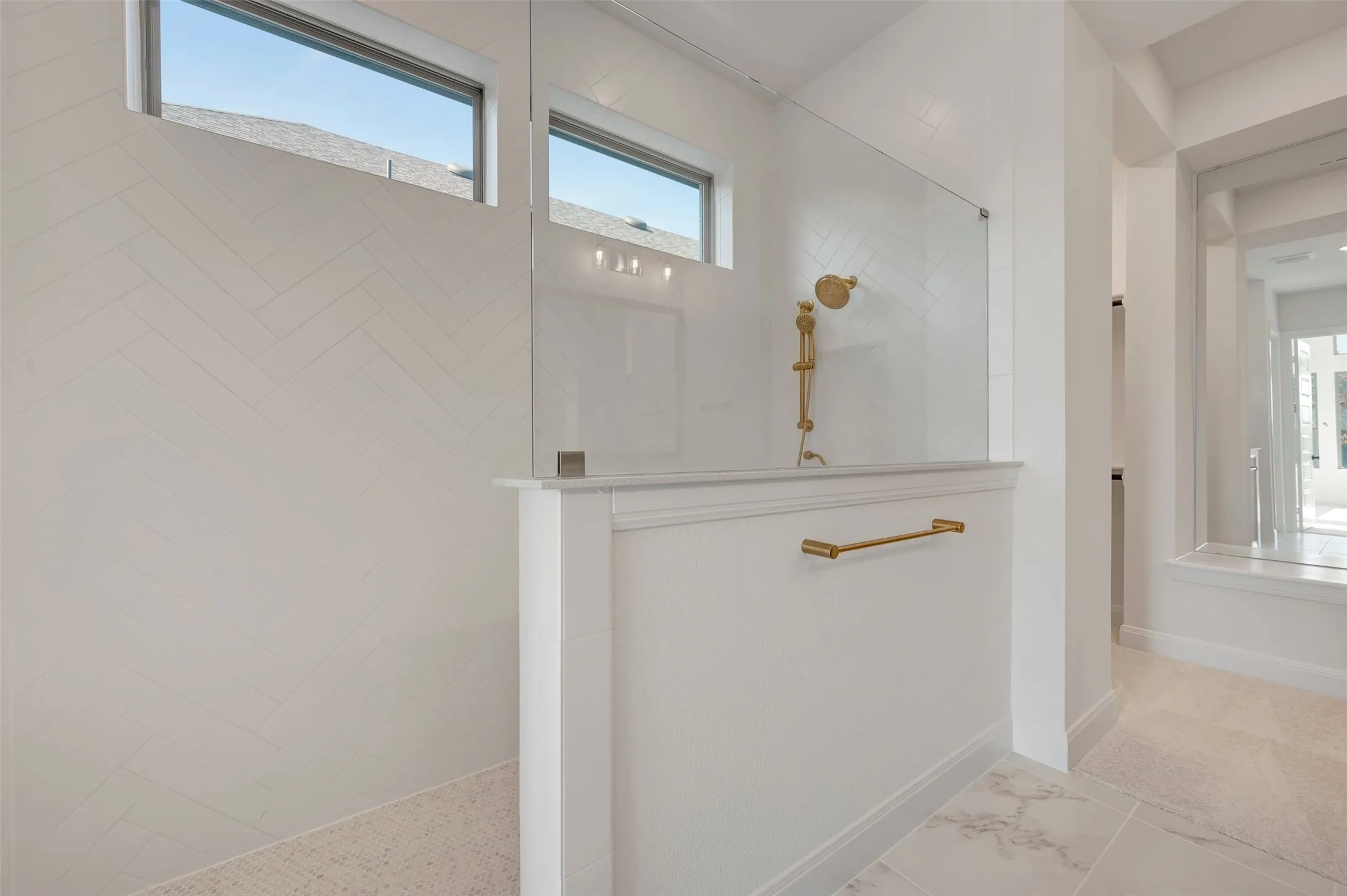 Walk-in shower featuring a glass enclosure, white herringbone tile, and gold-finish fixtures