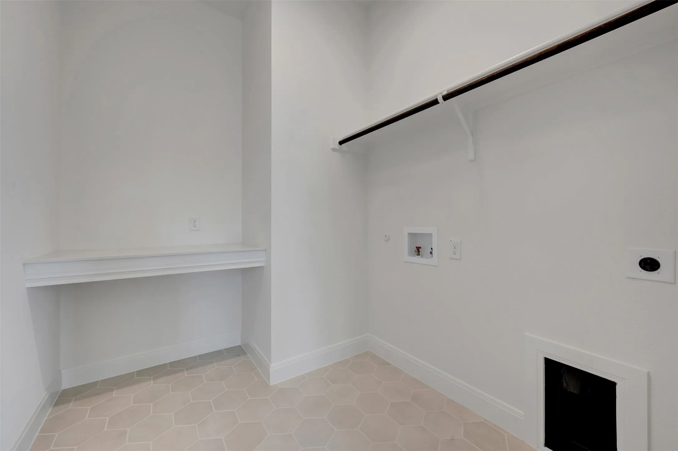 Utility room with hexagonal tile flooring, built-in shelving, and a dark-finished clothing rod