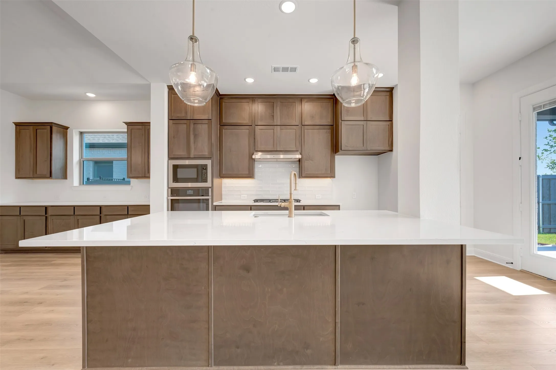 Kitchen featuring an expansive island with a white countertop and wood-finish cabinetry