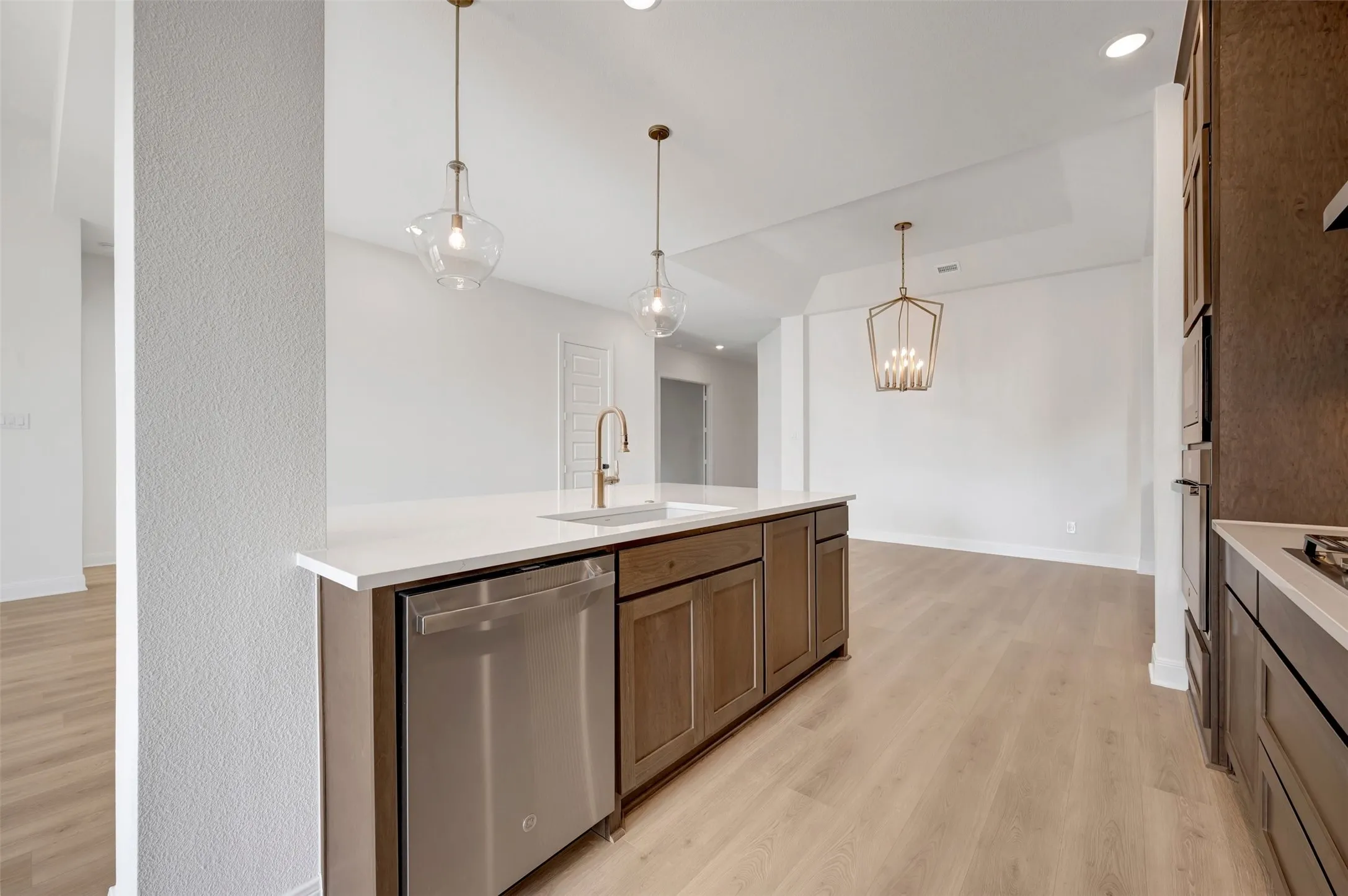 Kitchen island featuring a white countertop, undermount sink, and stainless steel dishwasher