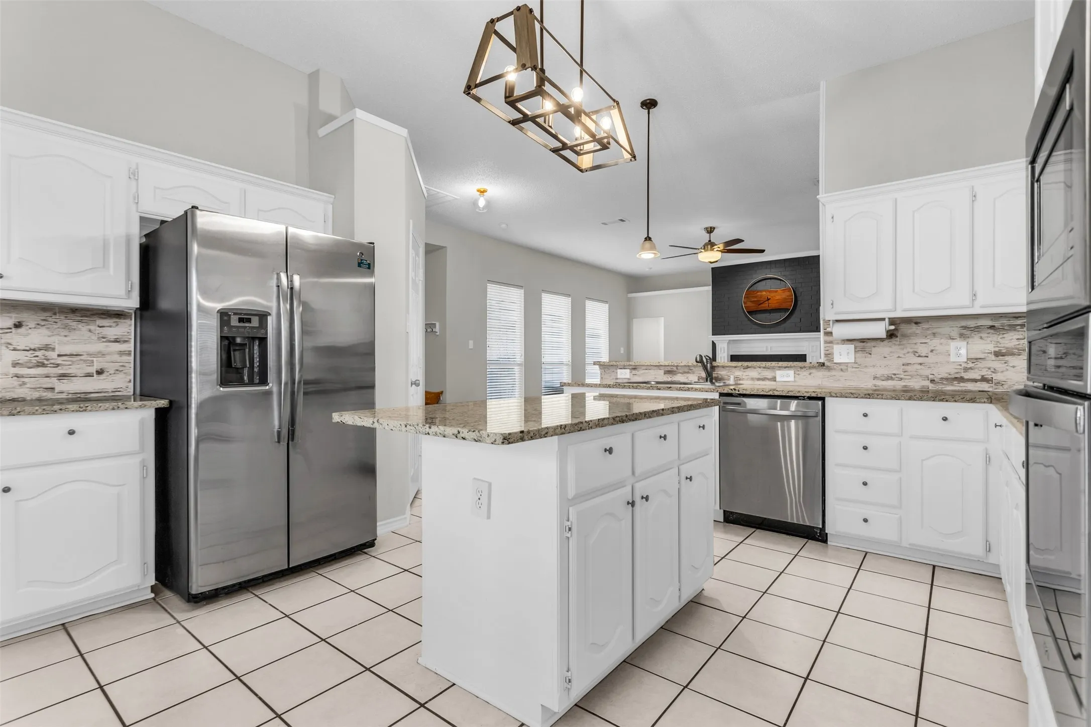 Bright kitchen setup featuring double ovens, a built-in microwave, and a tile backsplash.