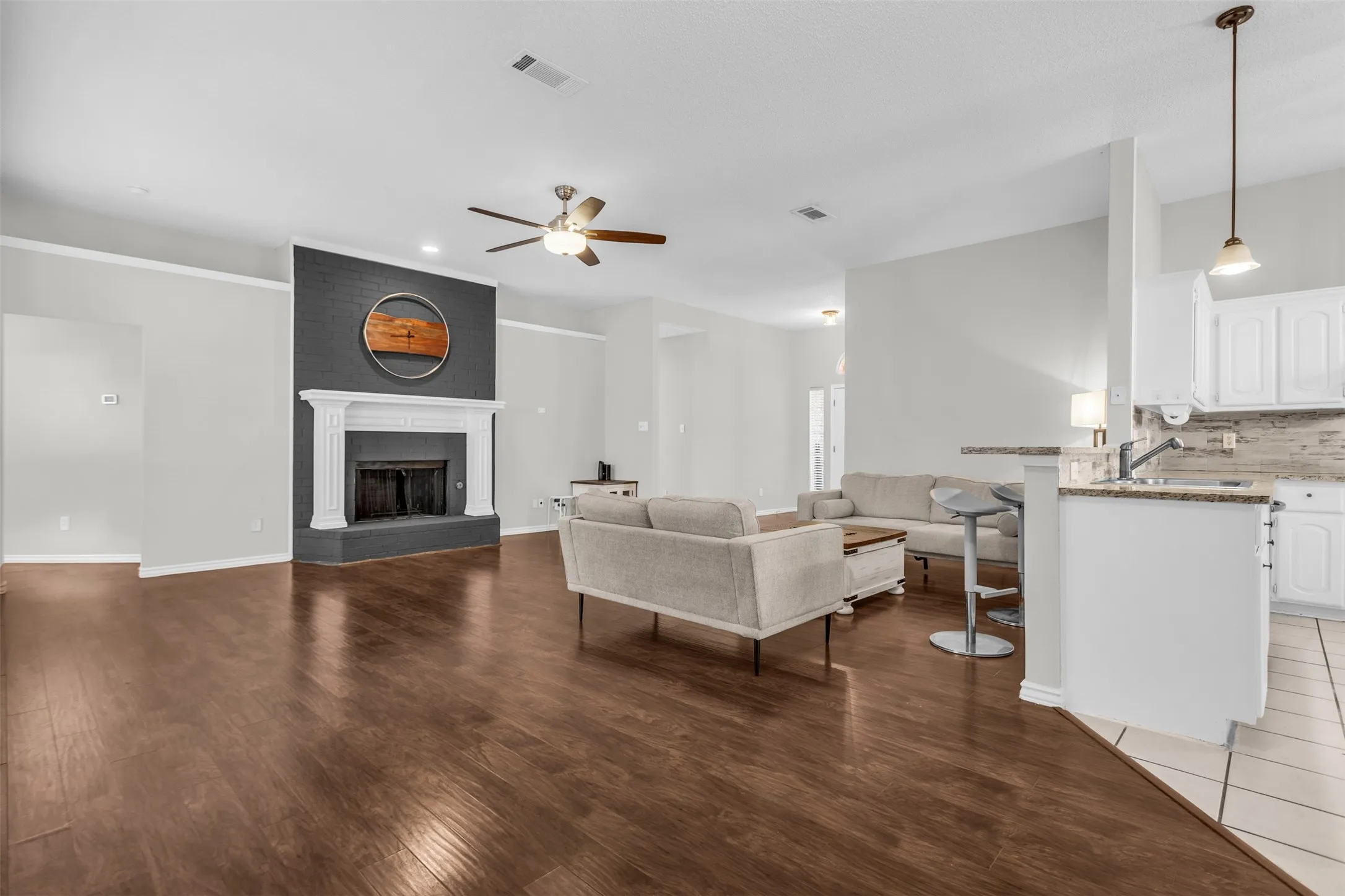 Light-filled living room featuring warm wood flooring, built-in entertainment shelving, and a cozy corner fireplace.