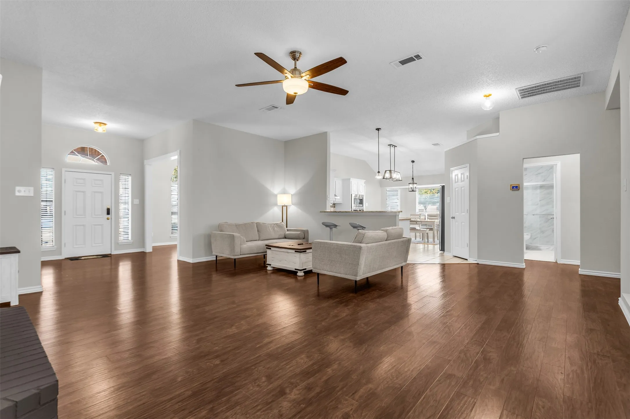 Expansive, open-concept main living area offering a ceiling fan, recessed lighting, and direct connection to the foyer.
